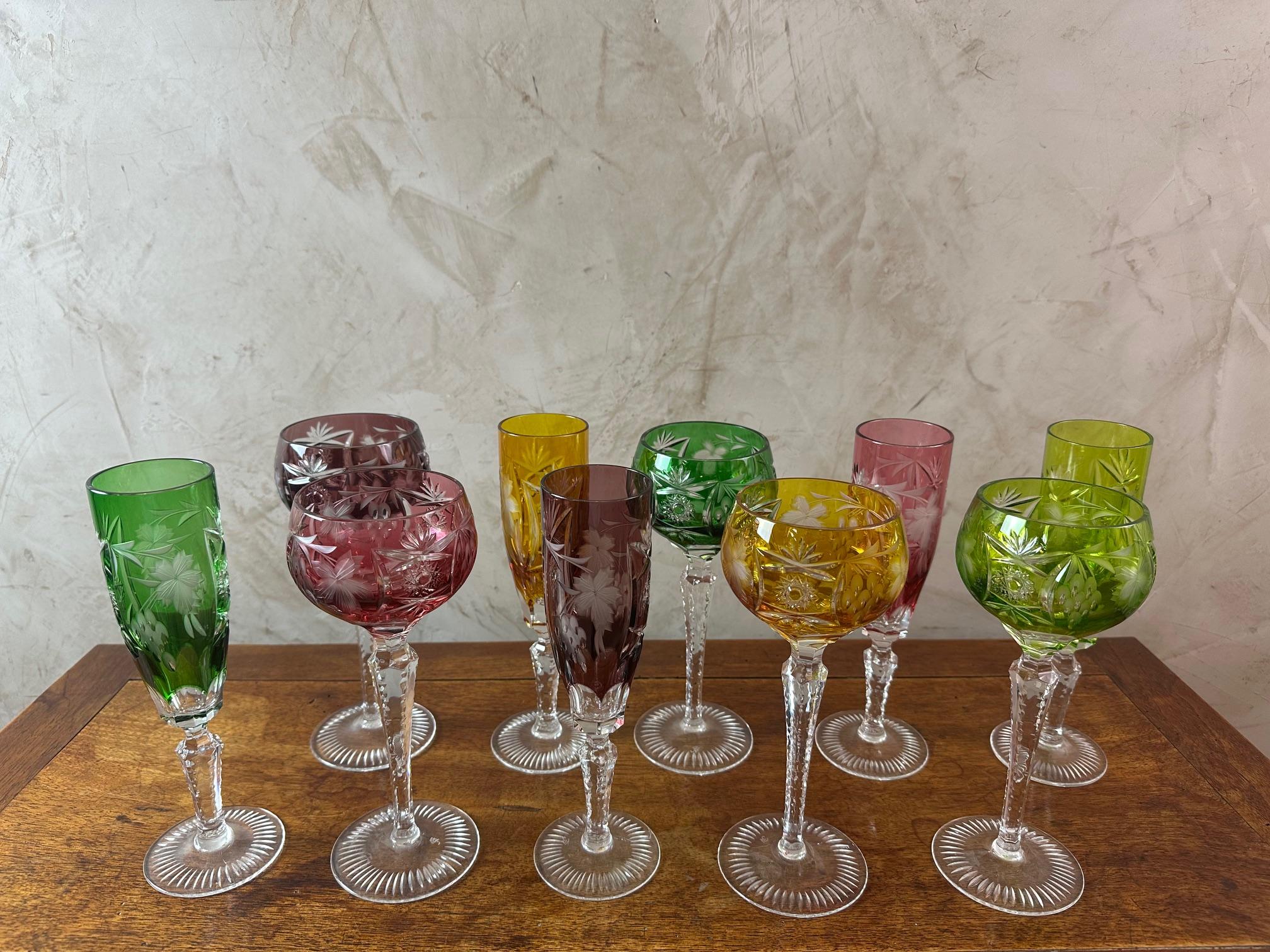 Very nice set of 10 colored glasses in Lorraine crystal, 5 wine glasses and 5 champagne flutes of several colors. A wine glass and a champagne glass of identical color. Signature of a crown on the foot which represents the crystal factory of