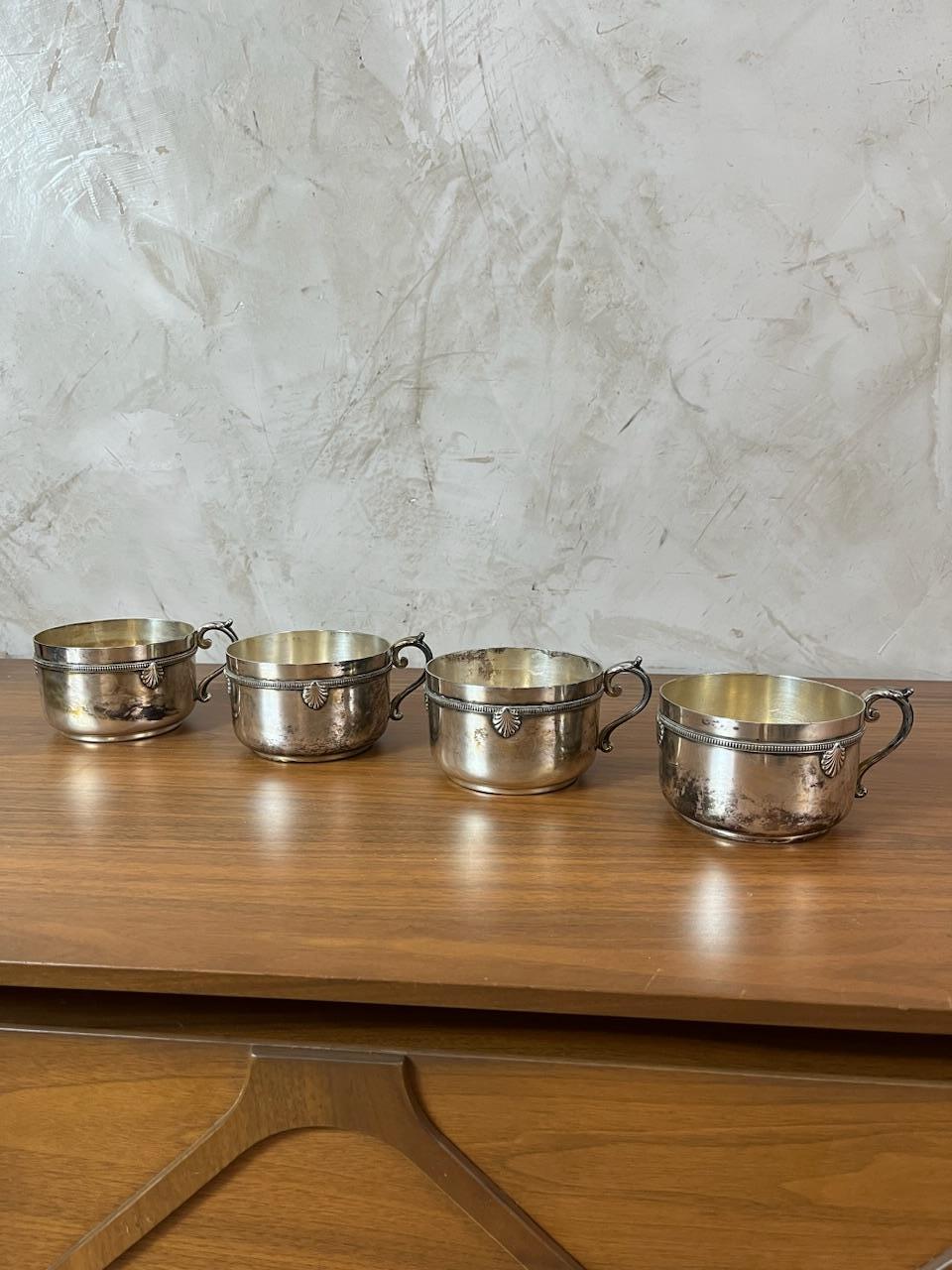 Set of four silver-plated cups and their matching saucers. Each piece features delicate shell motifs and fine handcrafted details, typical of early 20th-century pieces.

Engraved/chased shell decorations, elegant handles.

In good overall condition,