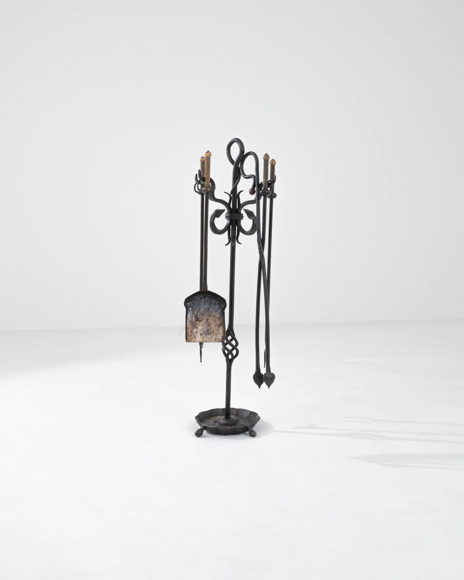 Combining the forms of traditional ironwork with graceful lines inspired by Art Nouveau, this vintage set of fireplace accessories offers a covetable home accent. Made in France in the 20th century, the central pole is embellished with an elegant