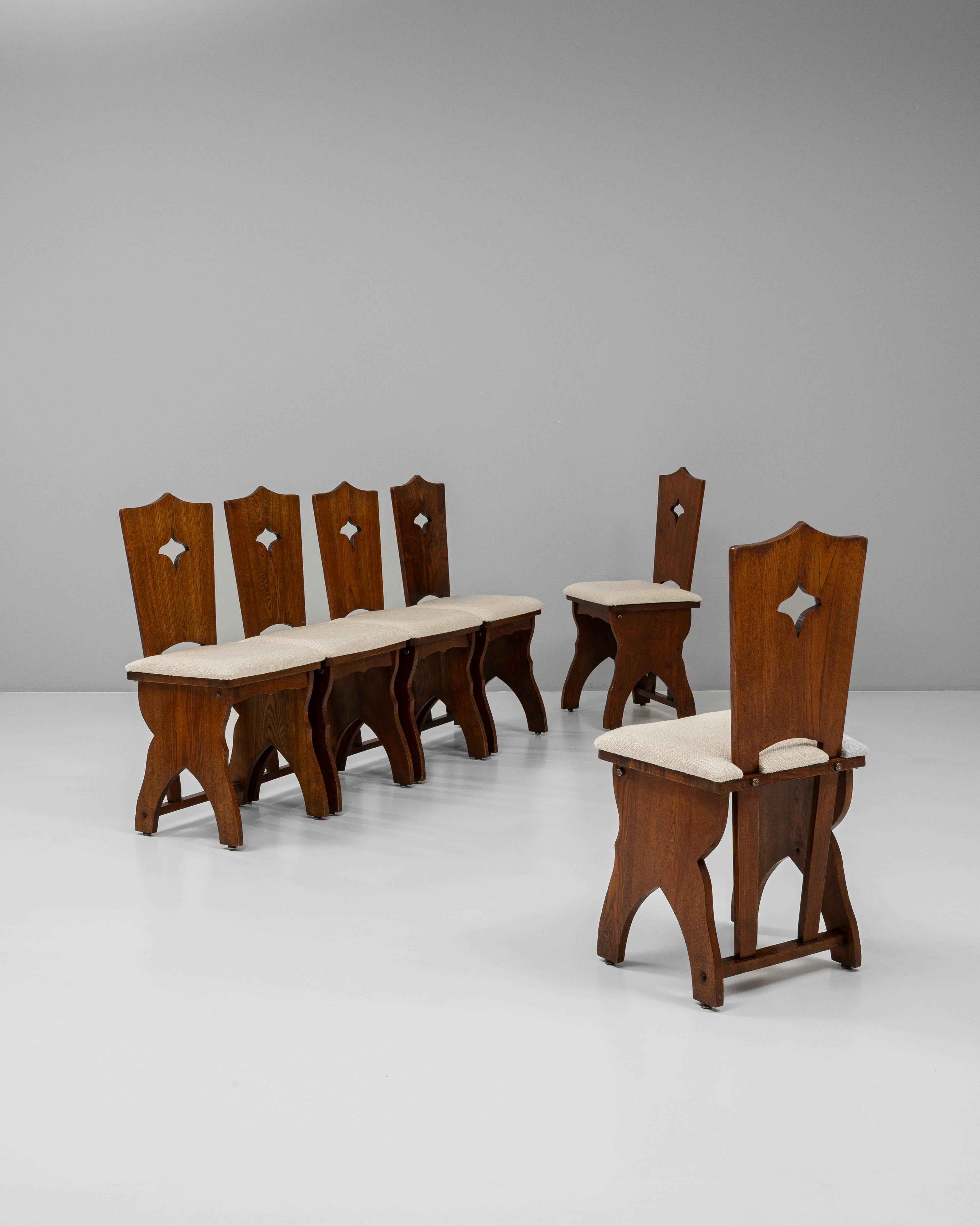 Cet ensemble français de six chaises de salle à manger en chêne du XXe siècle présente un mélange caractéristique de néo-gothique et d'artisanat rustique. Chaque chaise est construite en chêne massif avec des pieds élégamment arqués, des dossiers en