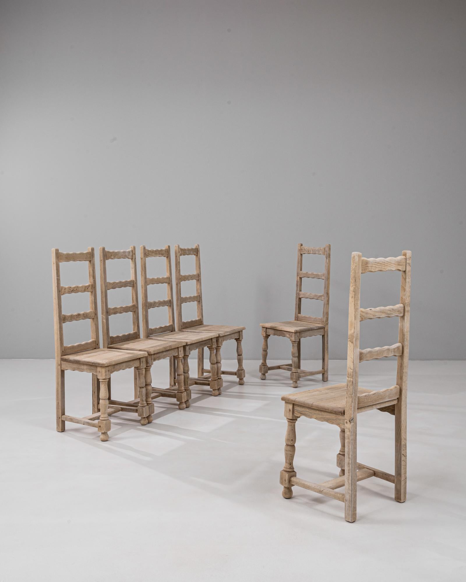 Cet ensemble français du 20e siècle de six chaises de salle à manger en chêne à dossier échelonné présente un savoir-faire traditionnel et un charme rustique intemporel. Fabriquée en chêne massif, chaque chaise présente un dossier en forme d'échelle