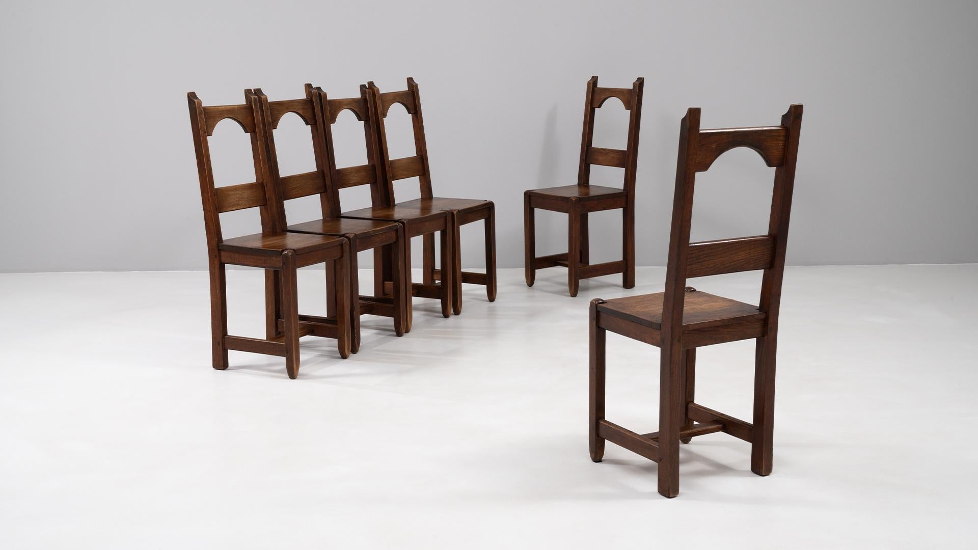 This set of six French wooden dining chairs from the 20th century presents a refined simplicity paired with enduring craftsmanship. Each chair is constructed from solid wood and retains its original patina, showcasing the natural depth of tone and