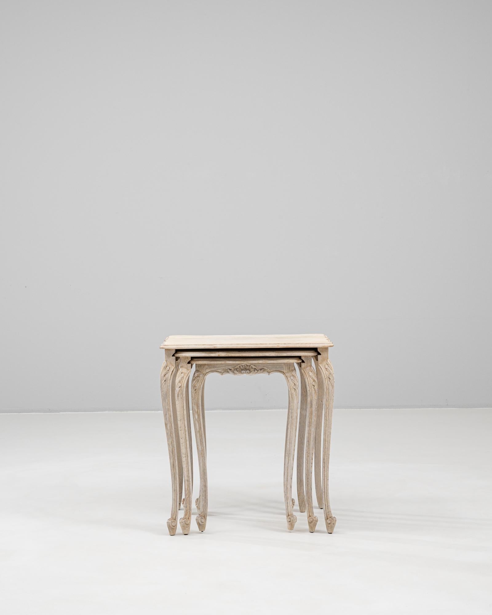 This 20th Century French Set of Three Oak Nesting Tables is a graceful example of Louis XV-style elegance in a practical, space-saving form. Crafted from solid oak, each table features a carved apron and cabriole legs with delicate floral motifs,