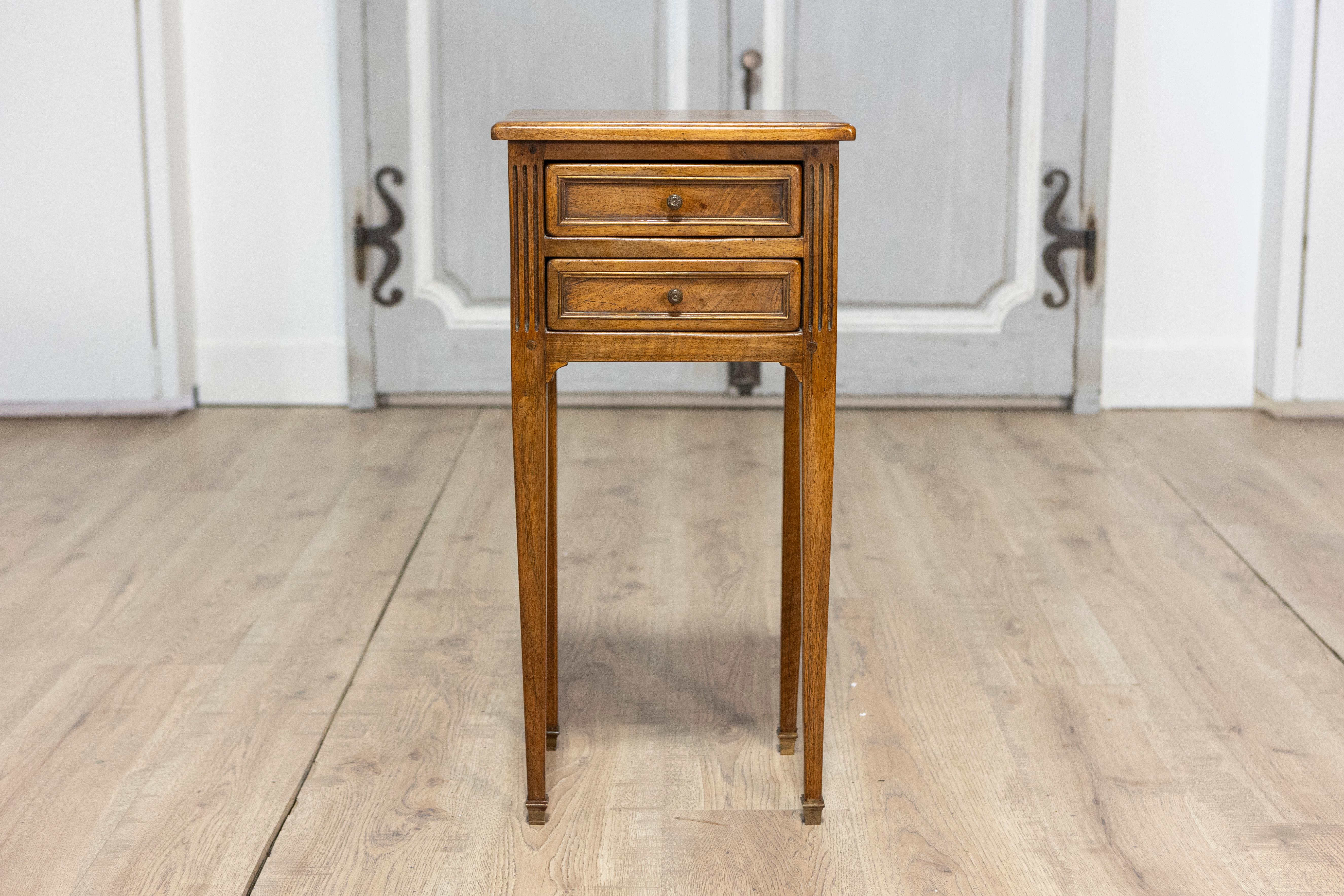 Cette élégante table d'appoint française du début du XXe siècle allie un savoir-faire raffiné à un design intemporel. Construit en bois dur aux tons chauds, il présente un plateau rectangulaire aux bords légèrement arrondis, soutenu par deux petits