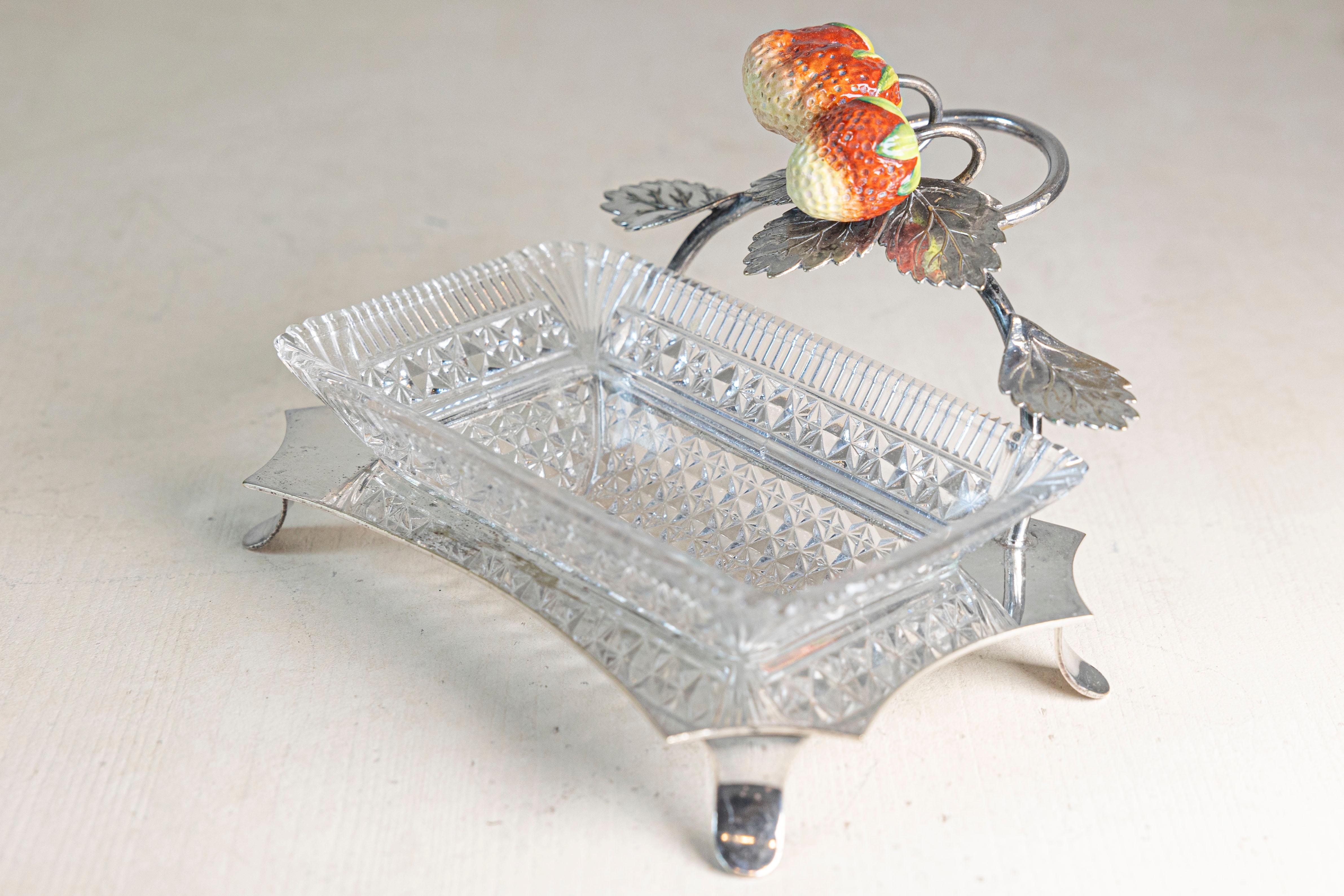 Ce plat de service en argent et verre taillé français du XXe siècle est un charmant exemple de design décoratif et fonctionnel. La base du plat est fabriquée en métal argenté, soutenue par des pieds aux formes élégantes qui élèvent la pièce et lui
