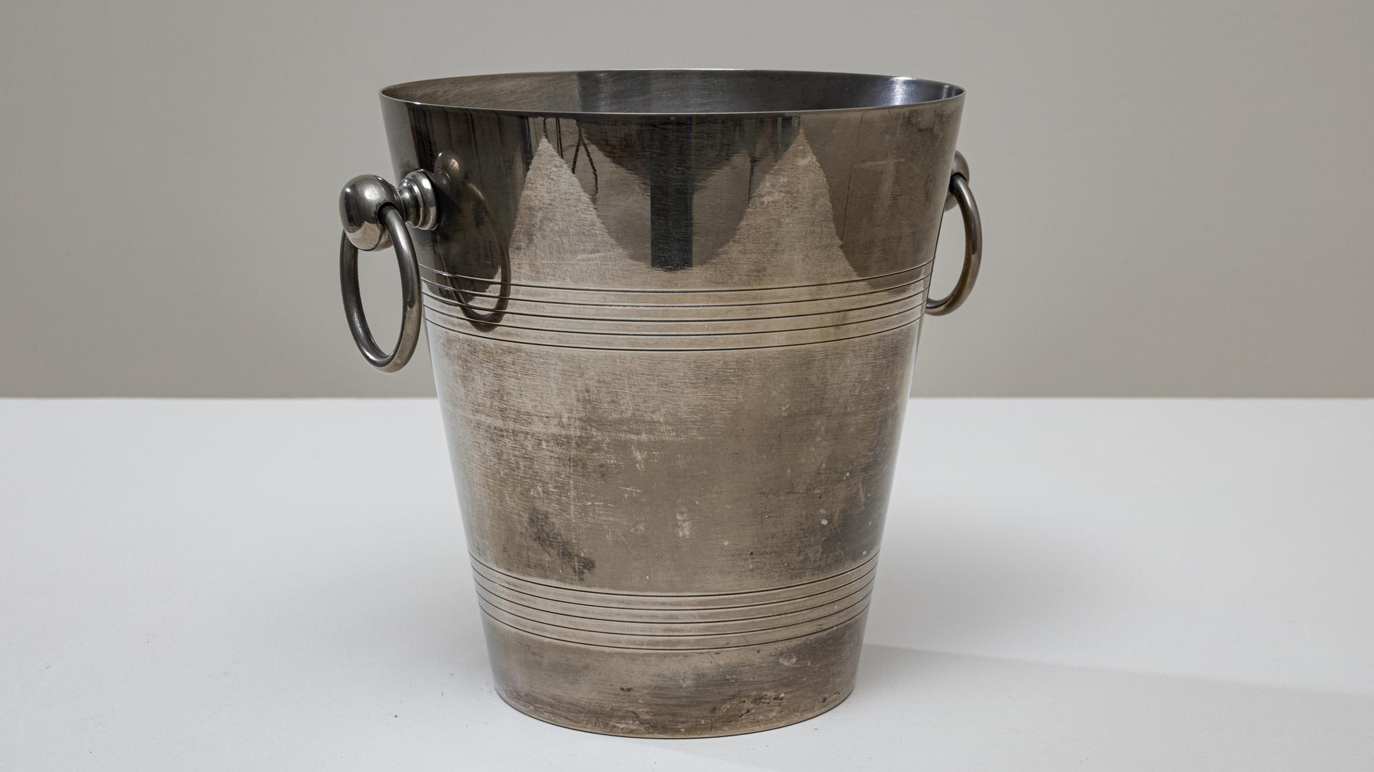 Seau à champagne en métal argenté français du XXe siècle, à la silhouette élancée et effilée, orné d'une bande décorative raffinée. Le corps cylindrique lisse est rehaussé d'anneaux horizontaux finement incisés près du haut et du bas, ce qui ajoute