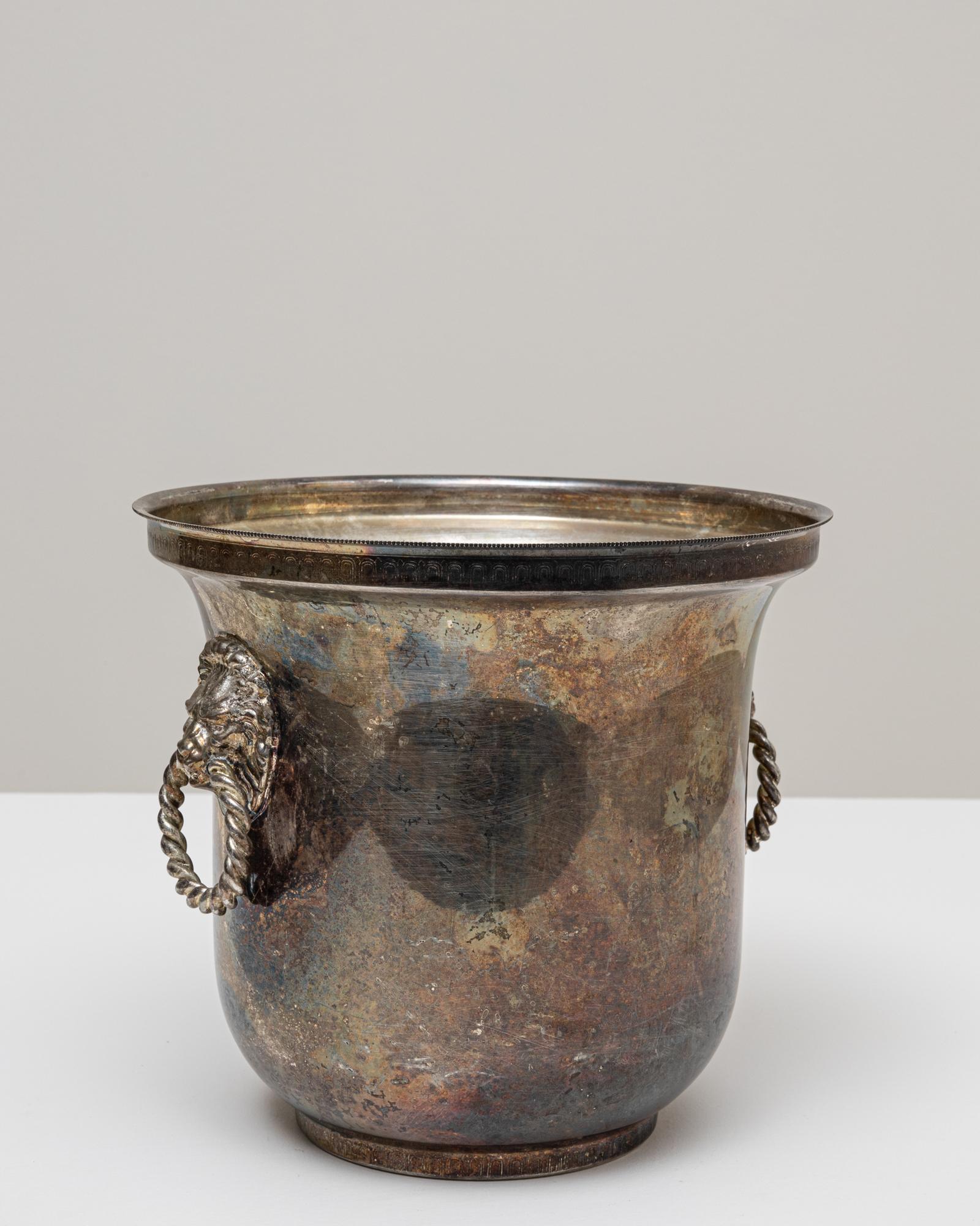 Seau à champagne en métal argenté français du 20e siècle, dont la surface richement vieillie met en valeur les décennies d'utilisation et de fabrication. Le corps arrondi et légèrement évasé repose sur un petit pied surélevé, conférant à la pièce