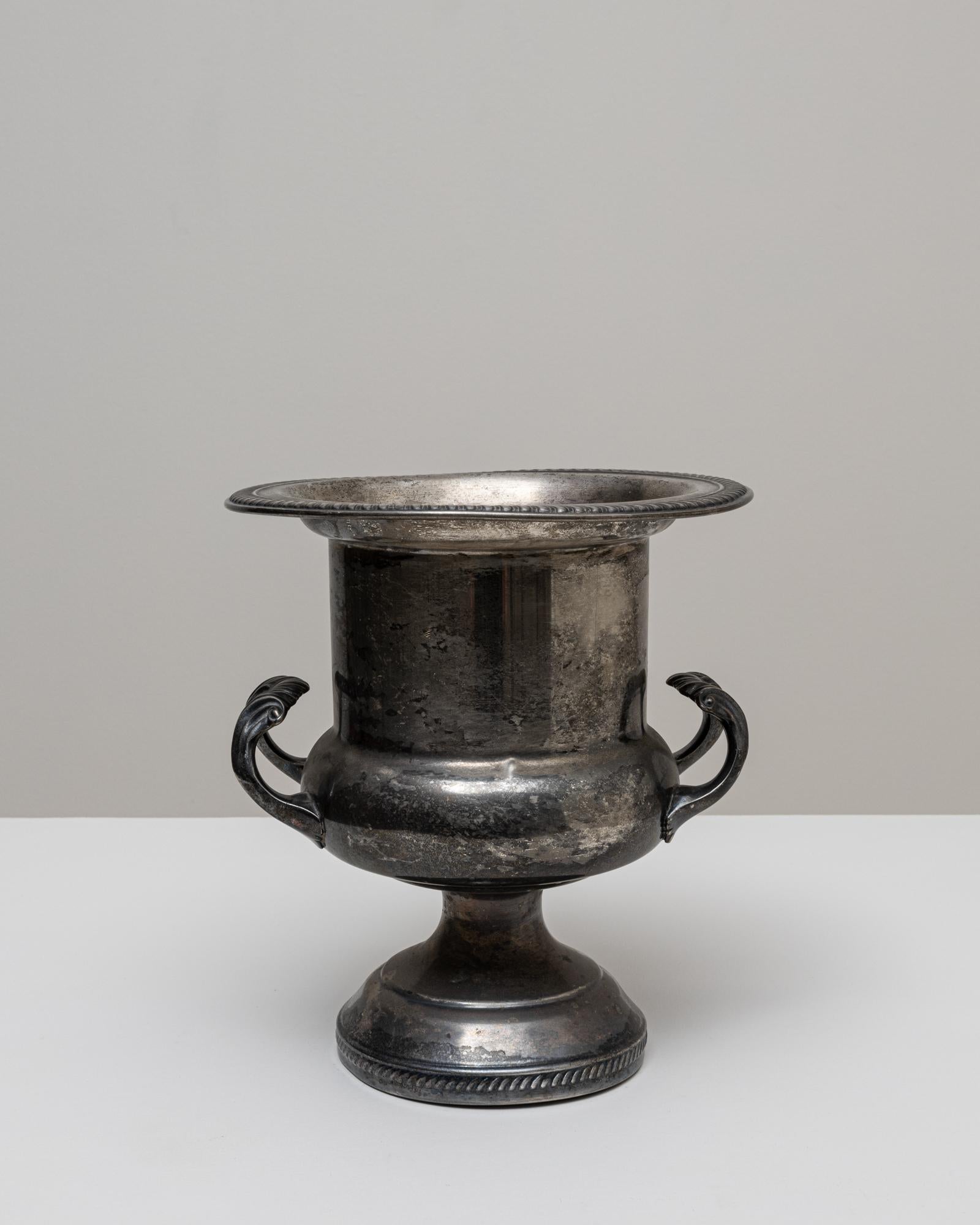 A 20th Century French silver-plated champagne bucket distinguished by its tall, urn-like silhouette and richly detailed craftsmanship. The flared rim features a finely incised border, adding subtle ornamentation that enhances the piece’s classical