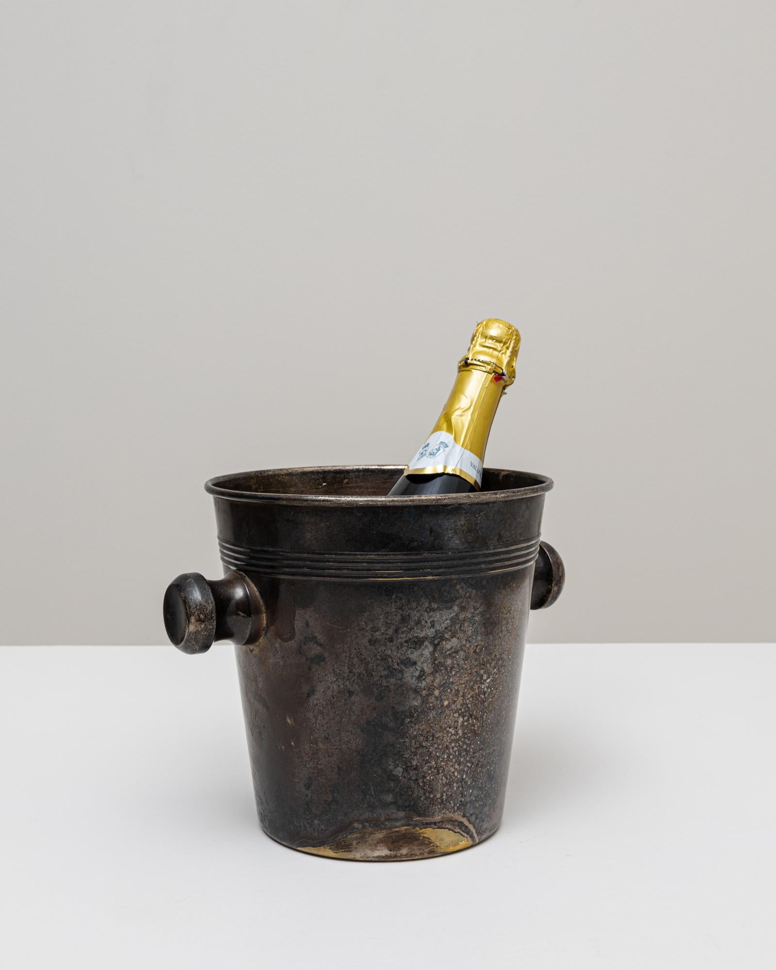 Un seau à champagne en métal argenté français du 20e siècle, à la présence sculpturale audacieuse et à la patine richement texturée. La forme cylindrique se rétrécit légèrement vers la base, tandis que le large bord évasé apporte un équilibre et une