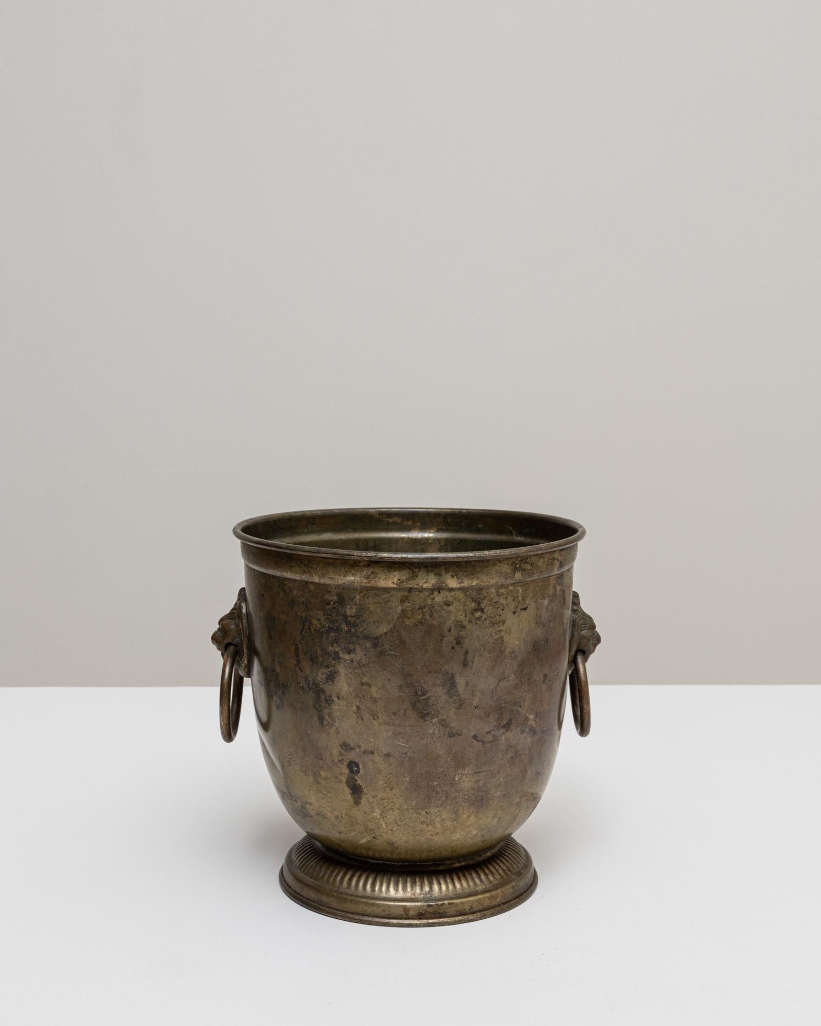 Ce seau à champagne en métal argenté français du XXe siècle présente une forme arrondie classique reposant sur un piédestal cannelé qui confère à la pièce une présence sculpturale élevée. La surface présente une patine chaude et naturellement