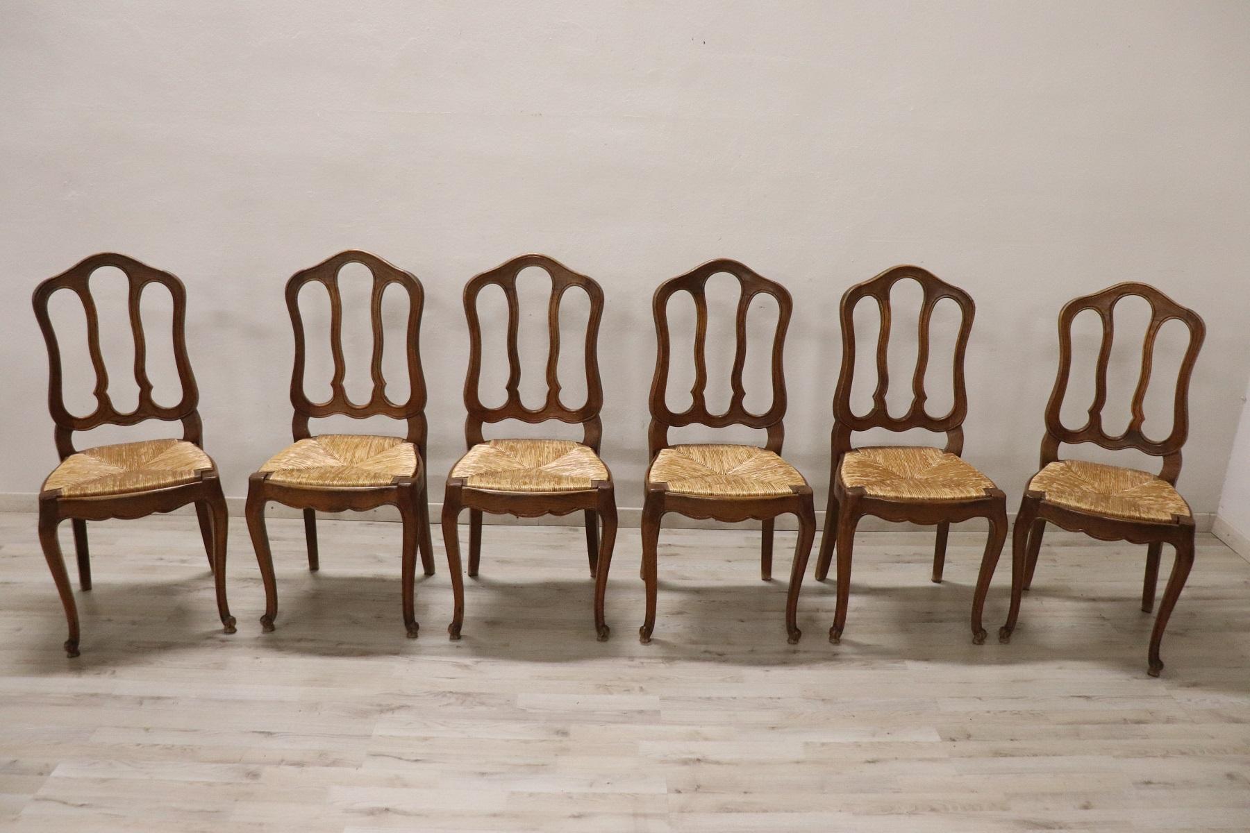 20th century Italian classical style dining room set of six chairs in solid chestnut wood. The chairs are very elegant with very slender and solid moving legs. The seat is wide and comfortable in rustic straw. The chairs are in perfect condition