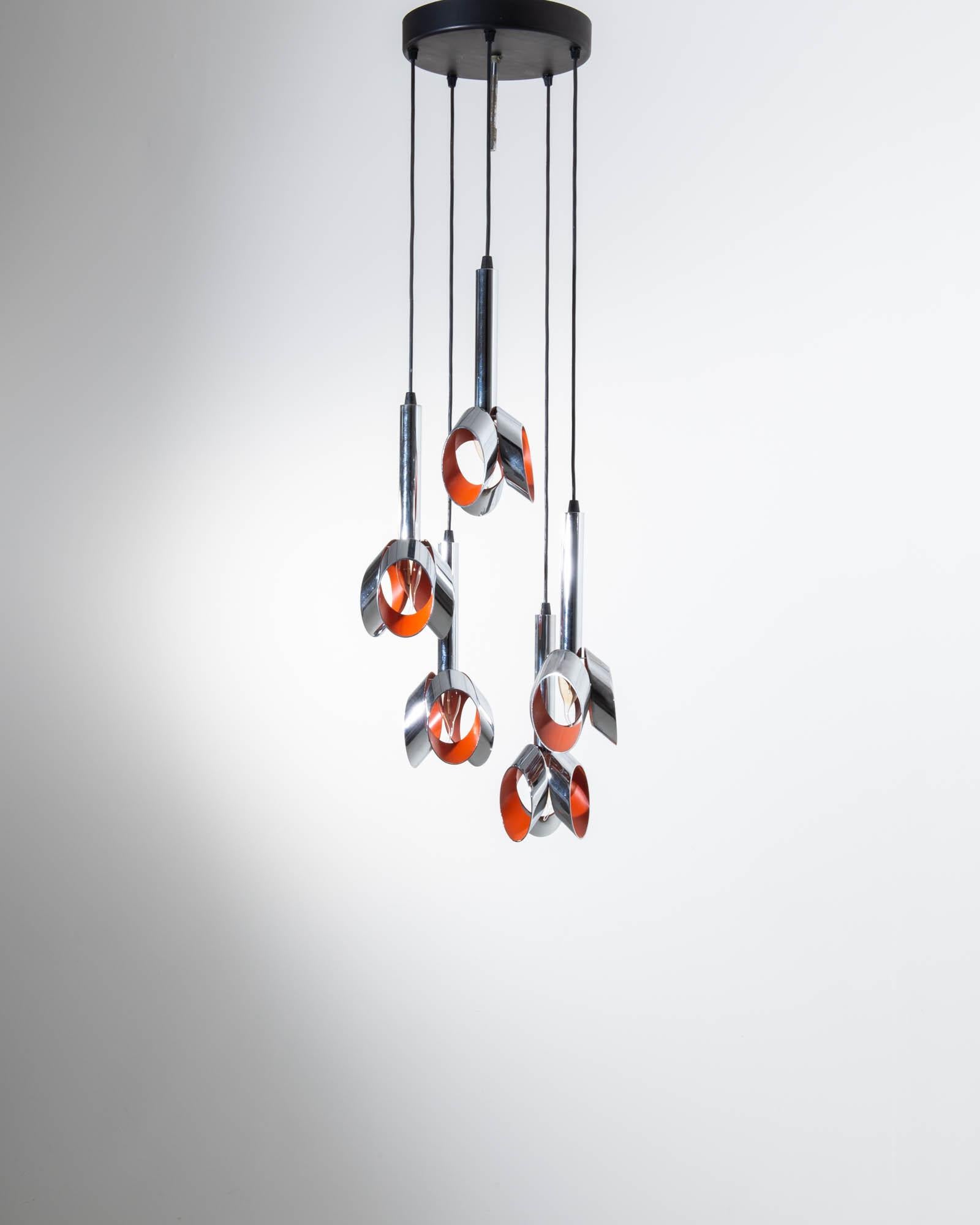 This striking Space Age chandelier makes a one of a kind accent. Made in France in the 20th century, the design combines formal elegance with a bold science fiction twist. The shades of the five pendant bulbs are composed of a trio of metal