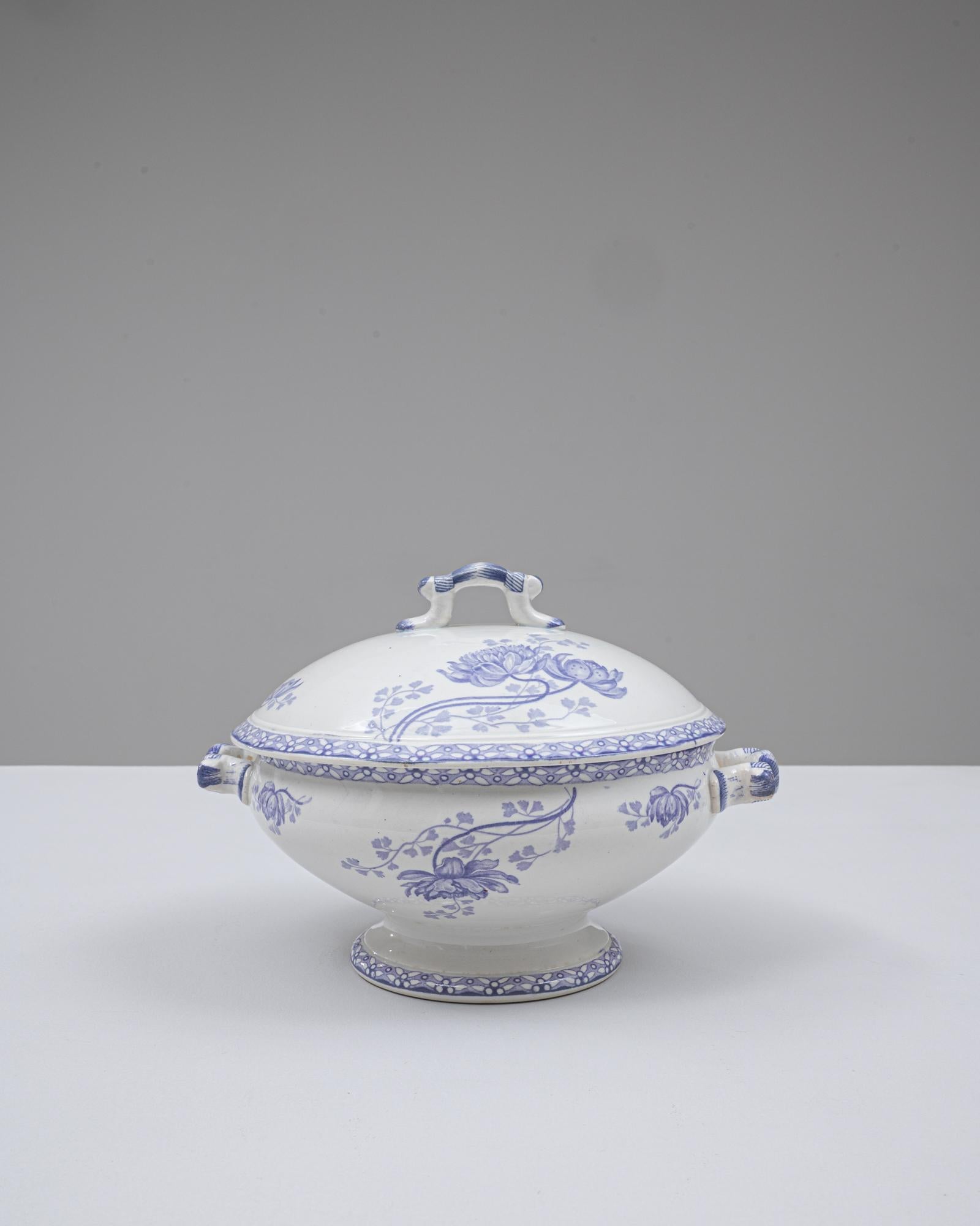 Cette soupière en porcelaine, édition spéciale française du 20e siècle, présente une élégante forme arrondie reposant sur un piédestal évasé, complété par un couvercle bombé doté d'une poignée en boucle sculptée. La glaçure blanche nette constitue