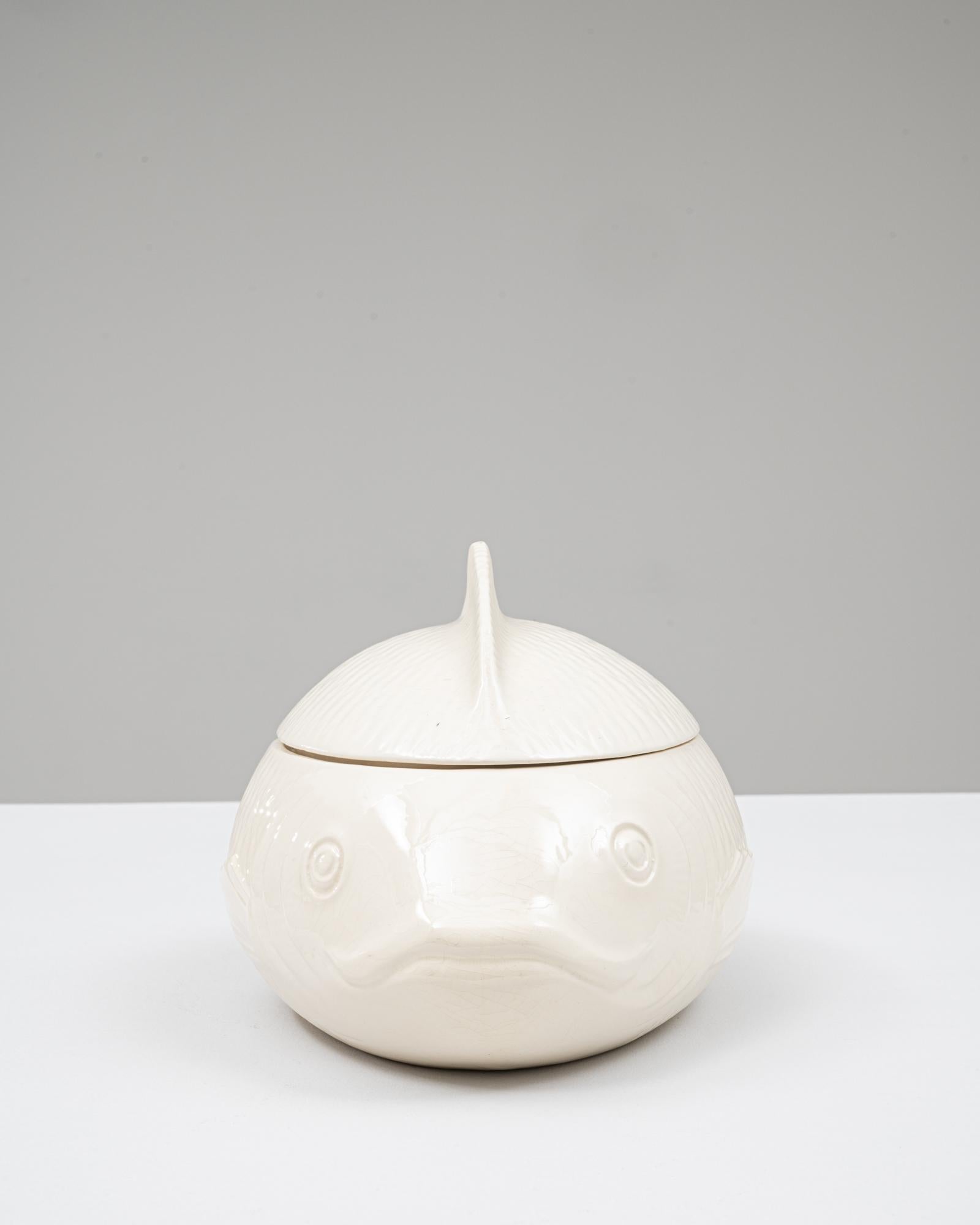 Cette soupière en porcelaine, édition spéciale française du 20e siècle, est façonnée dans une forme de poisson saisissante, offrant à la fois une présence sculpturale et un charme fonctionnel. La pièce présente une glaçure lisse et crémeuse qui met