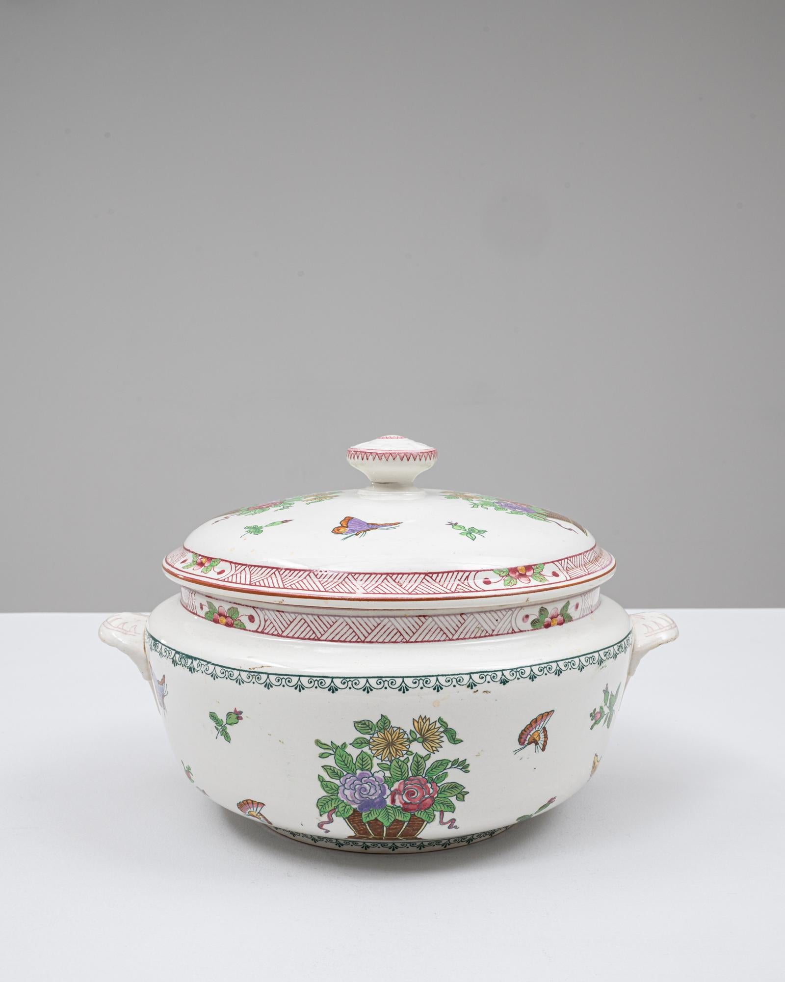 Cette soupière en porcelaine française du 20e siècle, édition spéciale, est une pièce vibrante et décorative qui se distingue par ses charmants motifs peints à la main et sa forme équilibrée et arrondie. Le couvercle est orné de délicats papillons,