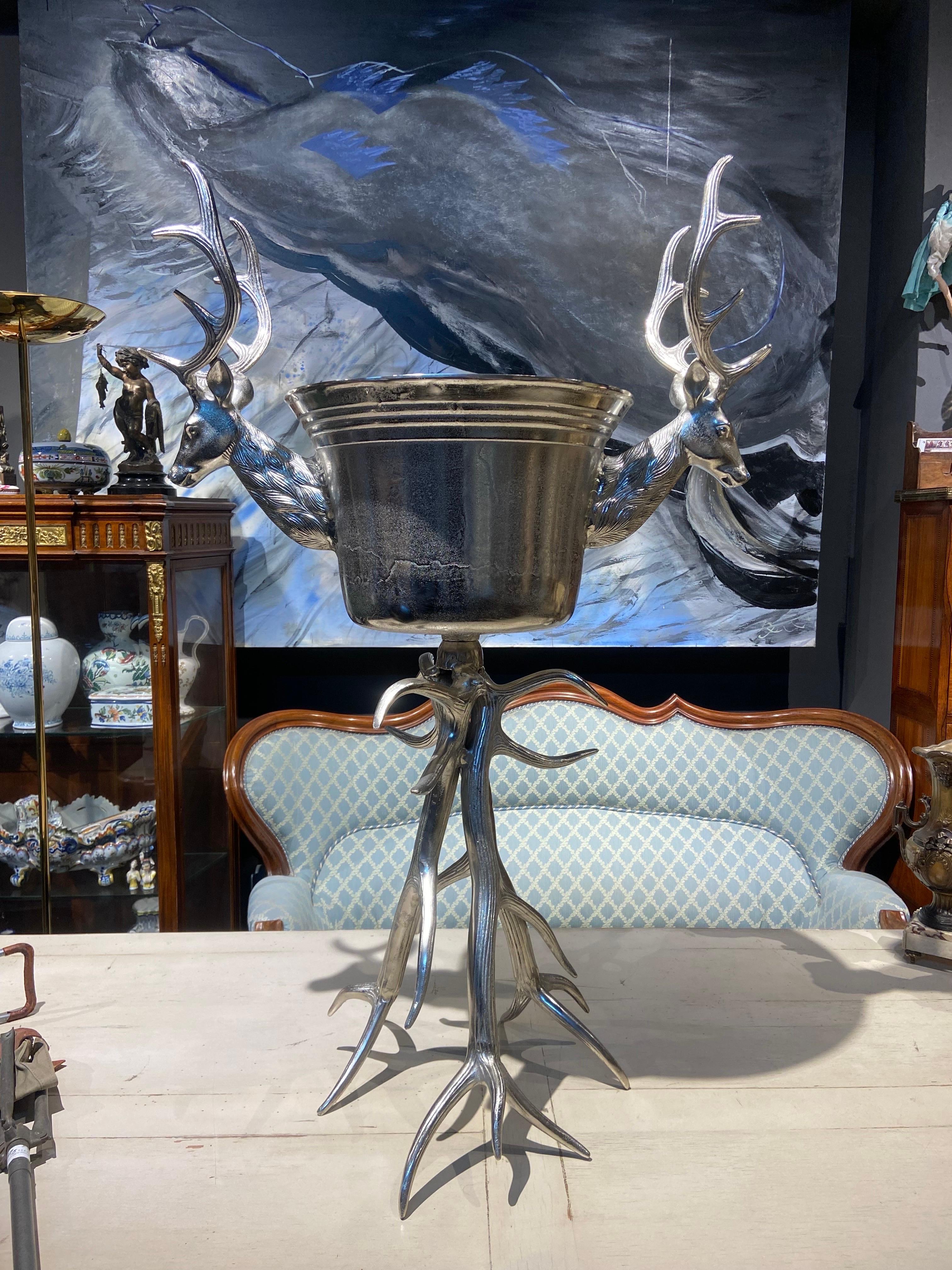French large metal wine cooler standing on a deer antler stand in very good condition. The stand is like deer horns, locked to give stability to the central bucket. The shining silver metal stag heads sit proud either side of it with gorgeous