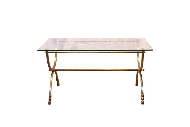 A 20th century french neoclassical style coffe table by Maison Charles.
A rectangular glass top above two circular brushed stainless steel legs joined by a stretcher. Ending on brass hoof feet and with brass details.