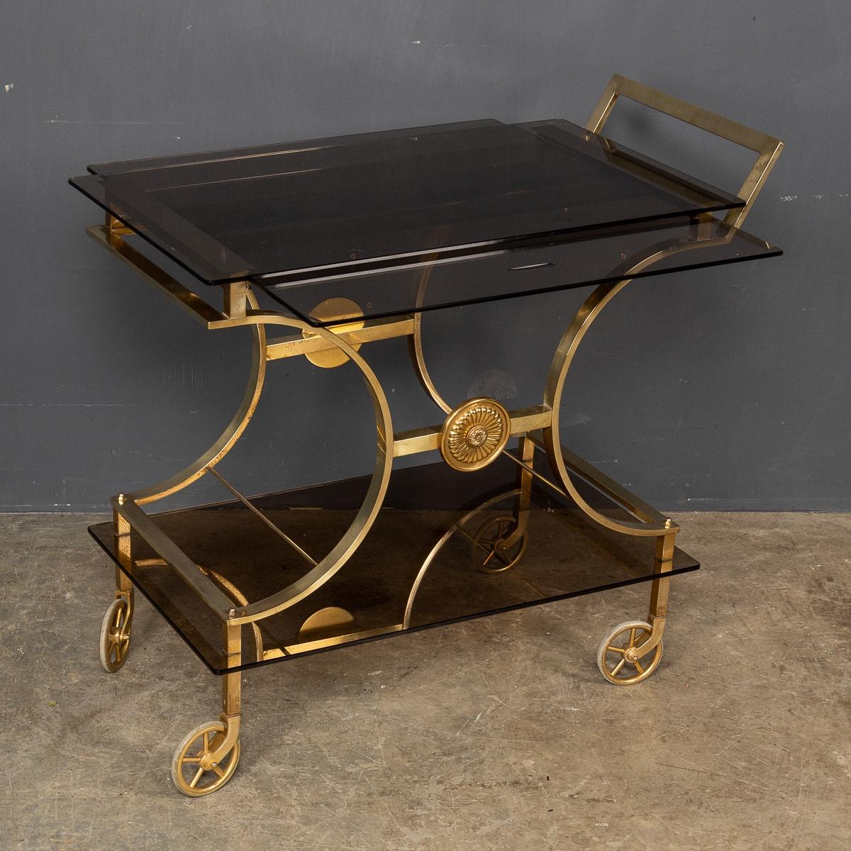 A mid 20th century French brass bar cart with retractable sliding serving trays set with smoked glass, by a renowned design house Maison Bagues.

CONDITION
In Great Condition - wear consistent with age.

SIZE
Height: 76cm
Width: 82cm
Depth: