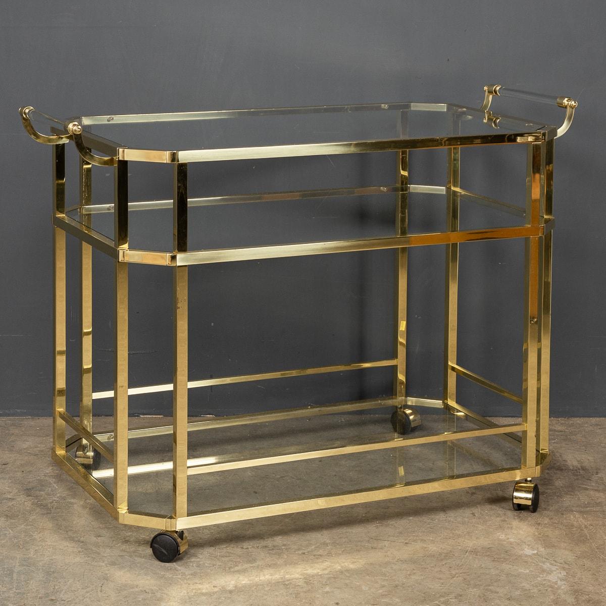 A French bar trolley composed of brass and glass with a lucite handle to one end, in fabulous condition with smooth rolling castors.

CONDITION
In Great Condition - wear consistent with age.

Size
Height: 75cm
Width: 106cm
Depth: 55cm.