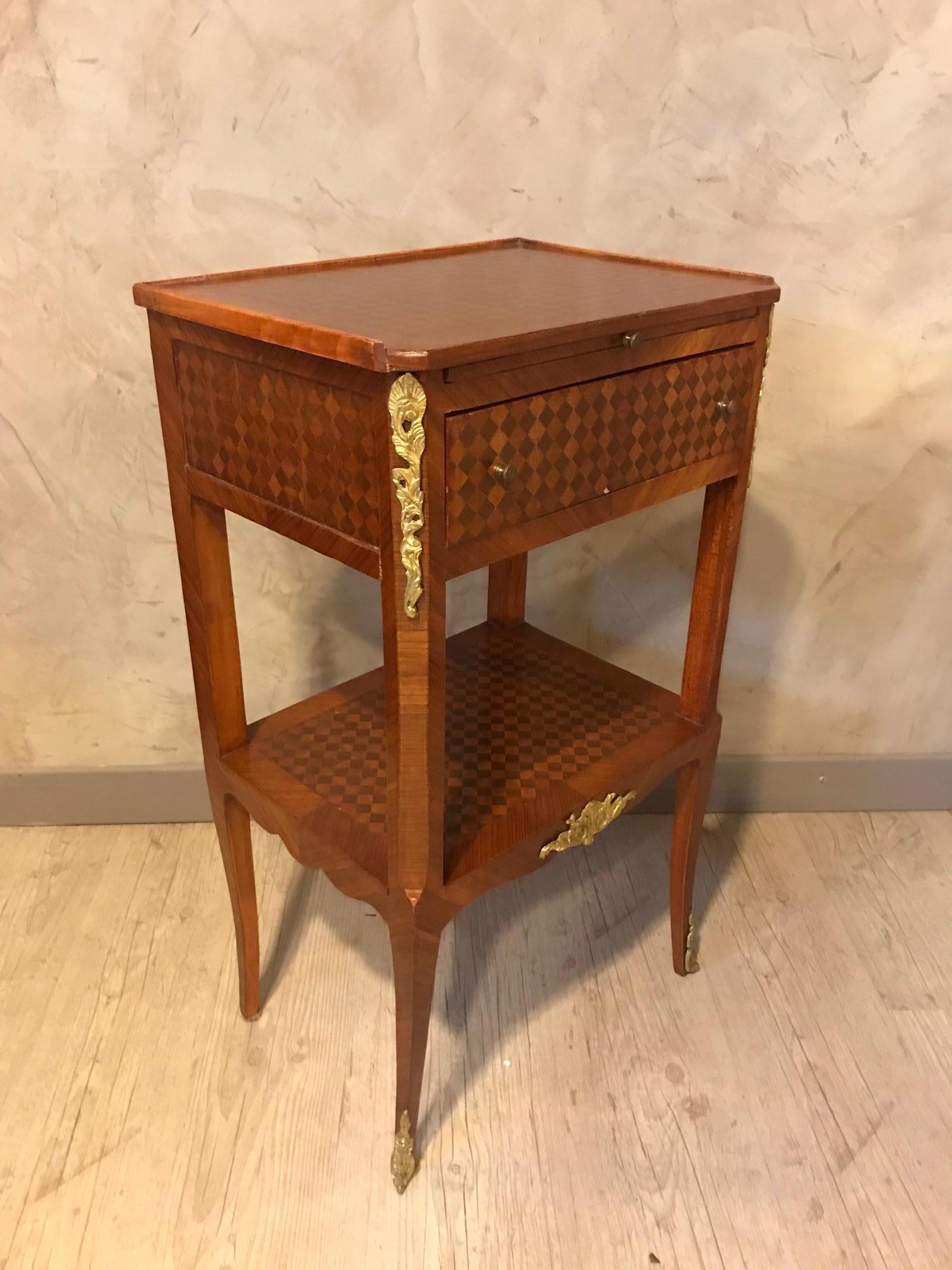 Very nice 20th century French Louis XV, Louis XVI transition style bedside made with mahogany marquetry and bronze fittings. A drawer.
Small hiding table with a leather on top that could be pulled.
Beautiful squared bi-colored marquetry. Gilded