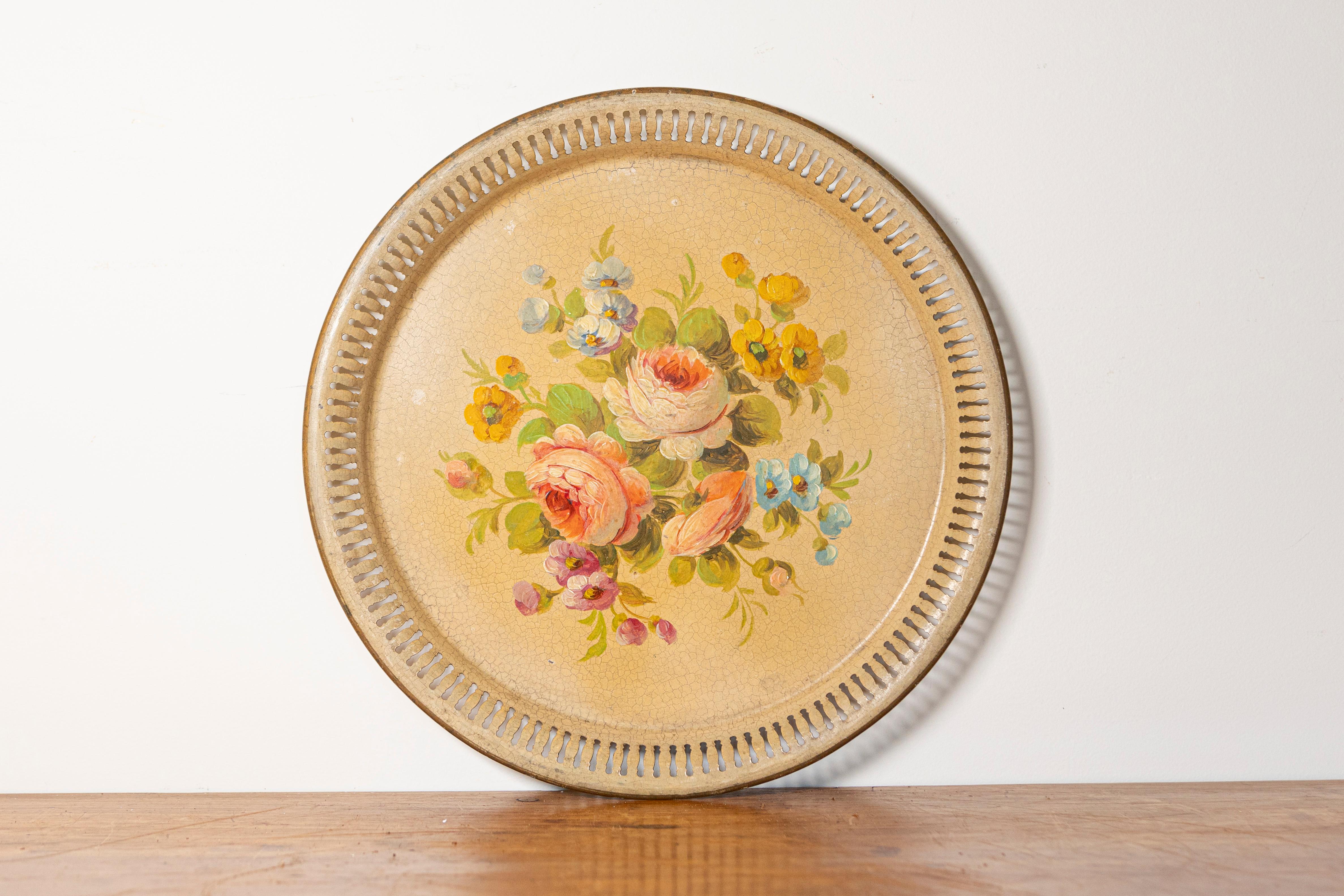 Dieses exquisite bemalte Blechtablett aus dem frühen 20. Jahrhundert ist ein schönes Beispiel für dekorative Kunst im Vintage-Stil. Mit einem zarten, handgemalten Blumendesign präsentiert das Mittelstück einen lebhaften Strauß aus Rosen,