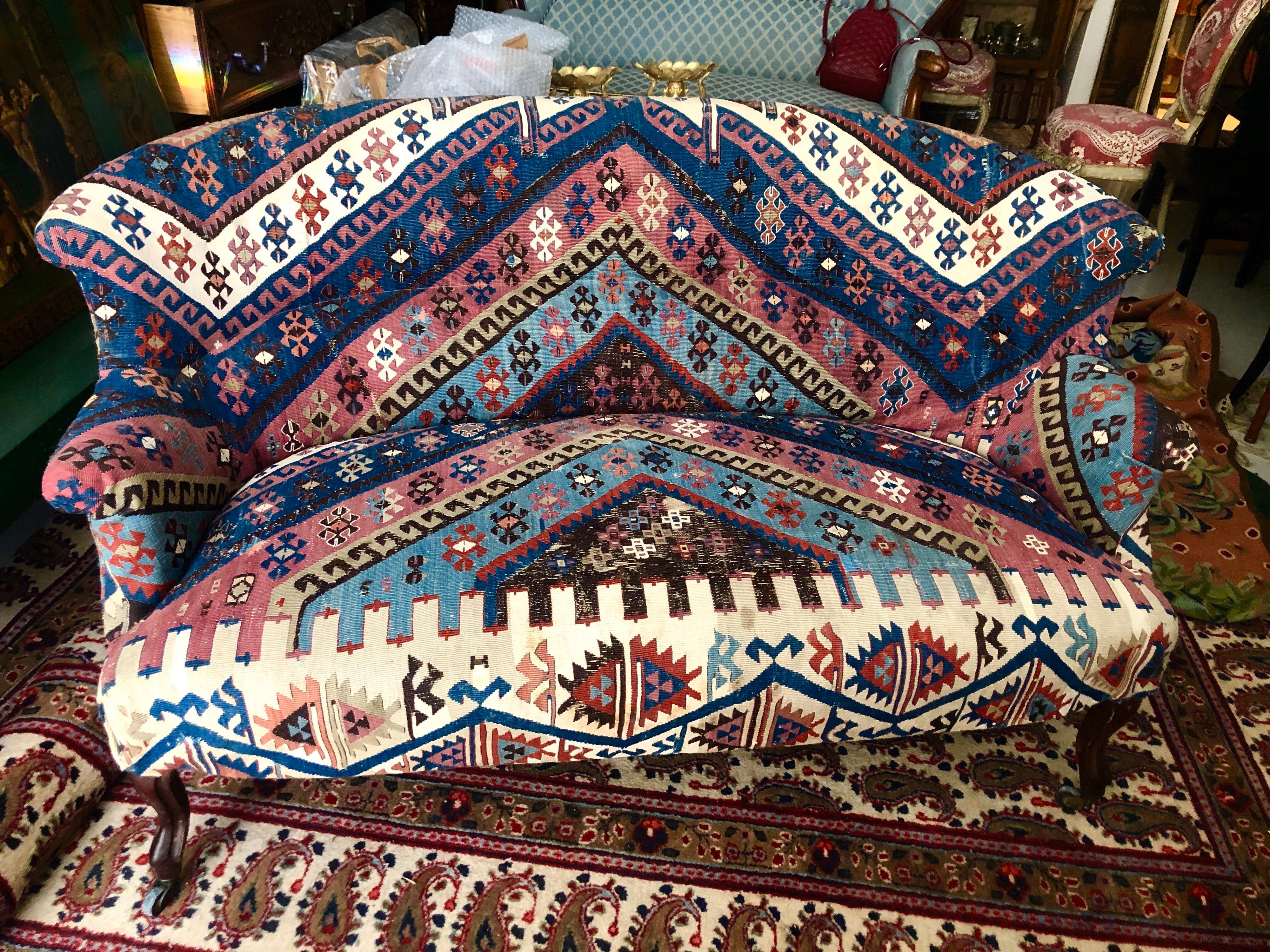 Rare et magnifique canapé français garni d'un tapis ancien en laine nouée à la main. La pièce repose sur quatre pieds en bois incurvés avec des roulettes en laiton à l'extrémité.
France, datant d'environ 1920.