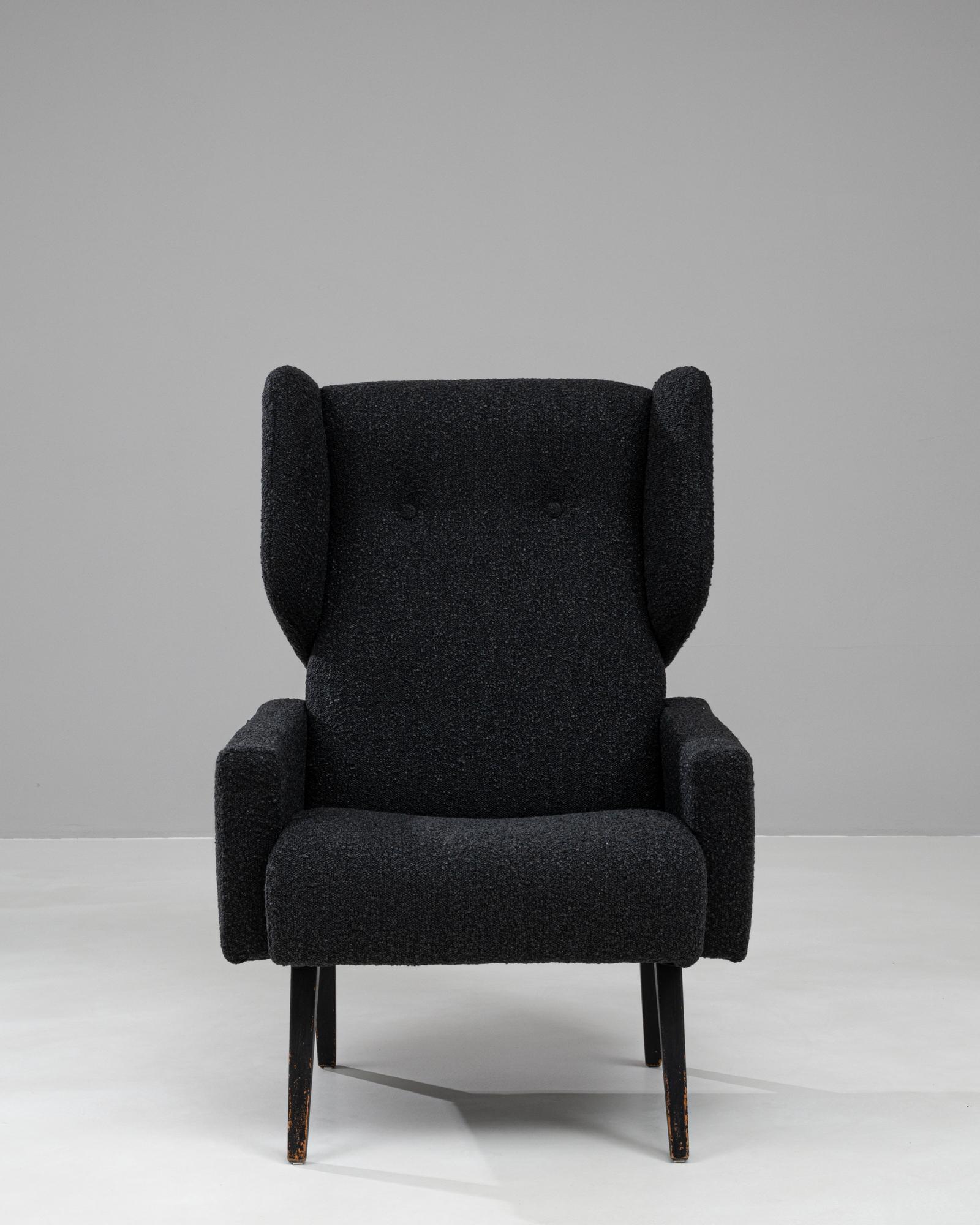 Questa straordinaria poltrona francese del XX secolo dona un tocco audace e modernista a qualsiasi spazio. Rivestita in tessuto bouclé nero, la sedia presenta uno schienale alto e alato che offre un fascino estetico e un comfort eccezionale. Le