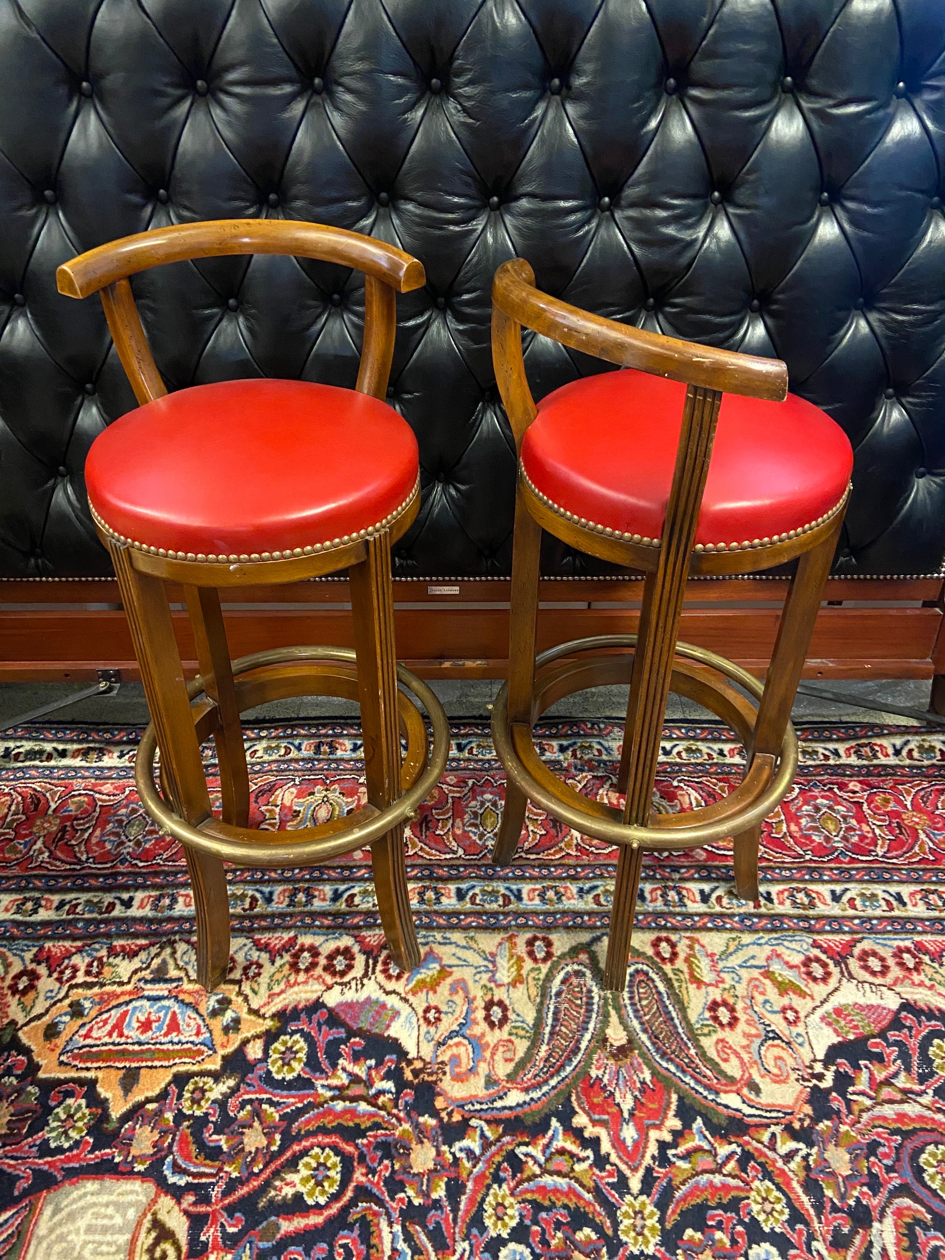 French vintage bar stools with round seat in red leather and comfortable low backrest. There is also a brass footstep at the bottom. 
Very good condition.
France, circa 1950.