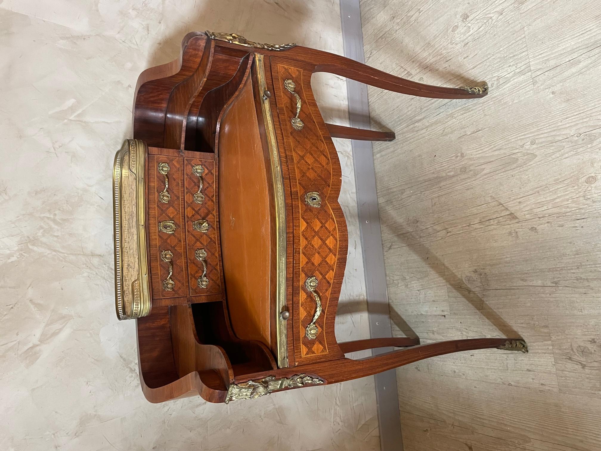 Early 20th-century walnut writing table or Bonheur du jour desk of serpentine form, the raised superstructure top with fitted shelves and brass gallery and marble top. Raised up on four out swept legs with gilt mounts. 
A leather writing space that