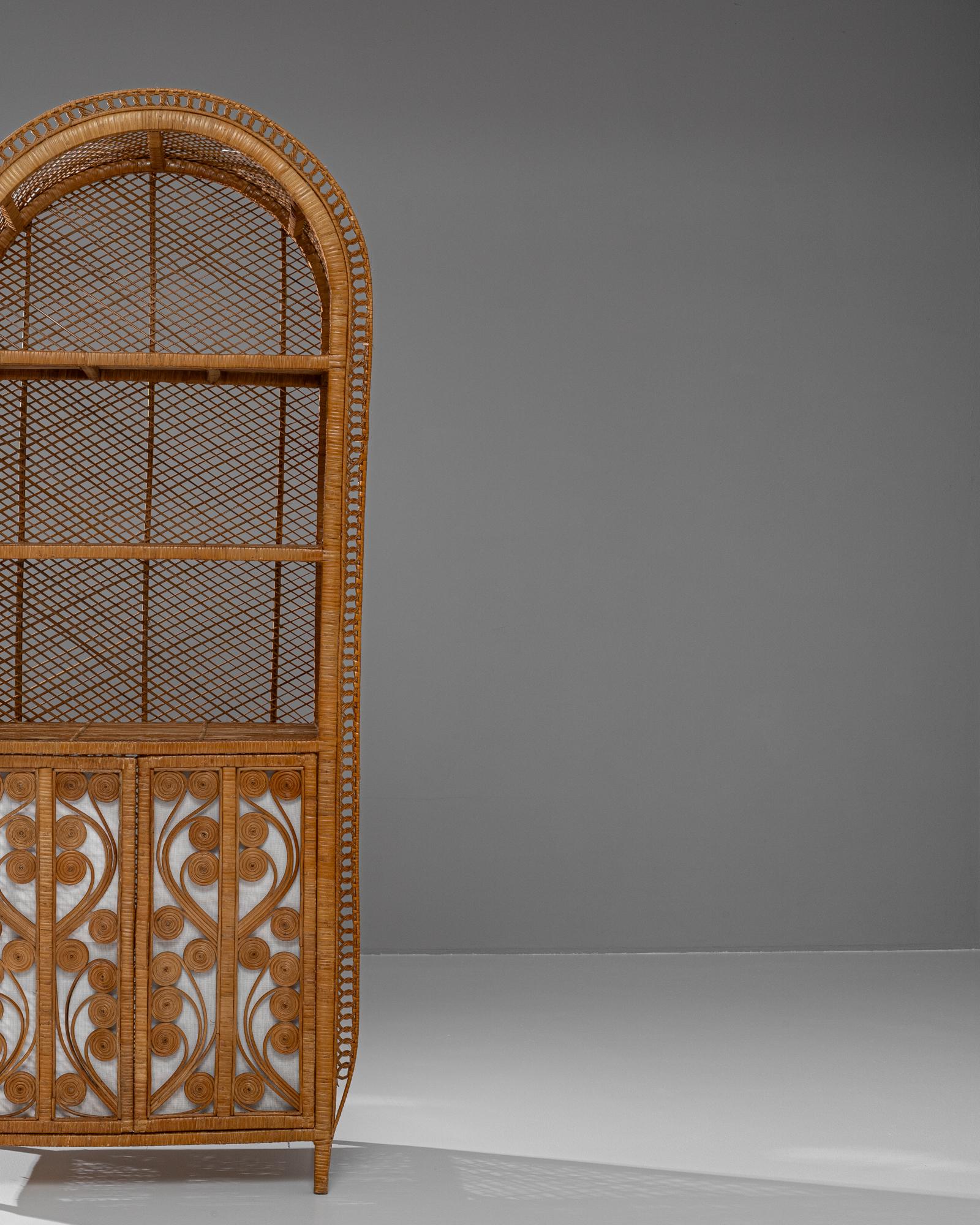 Questo affascinante mobile in vimini francese del XX secolo dona un tocco di estrosità vintage con il suo design in rattan intricato e la sua silhouette ad arco. La parte superiore è caratterizzata da un arioso reticolo aperto, ideale per esporre