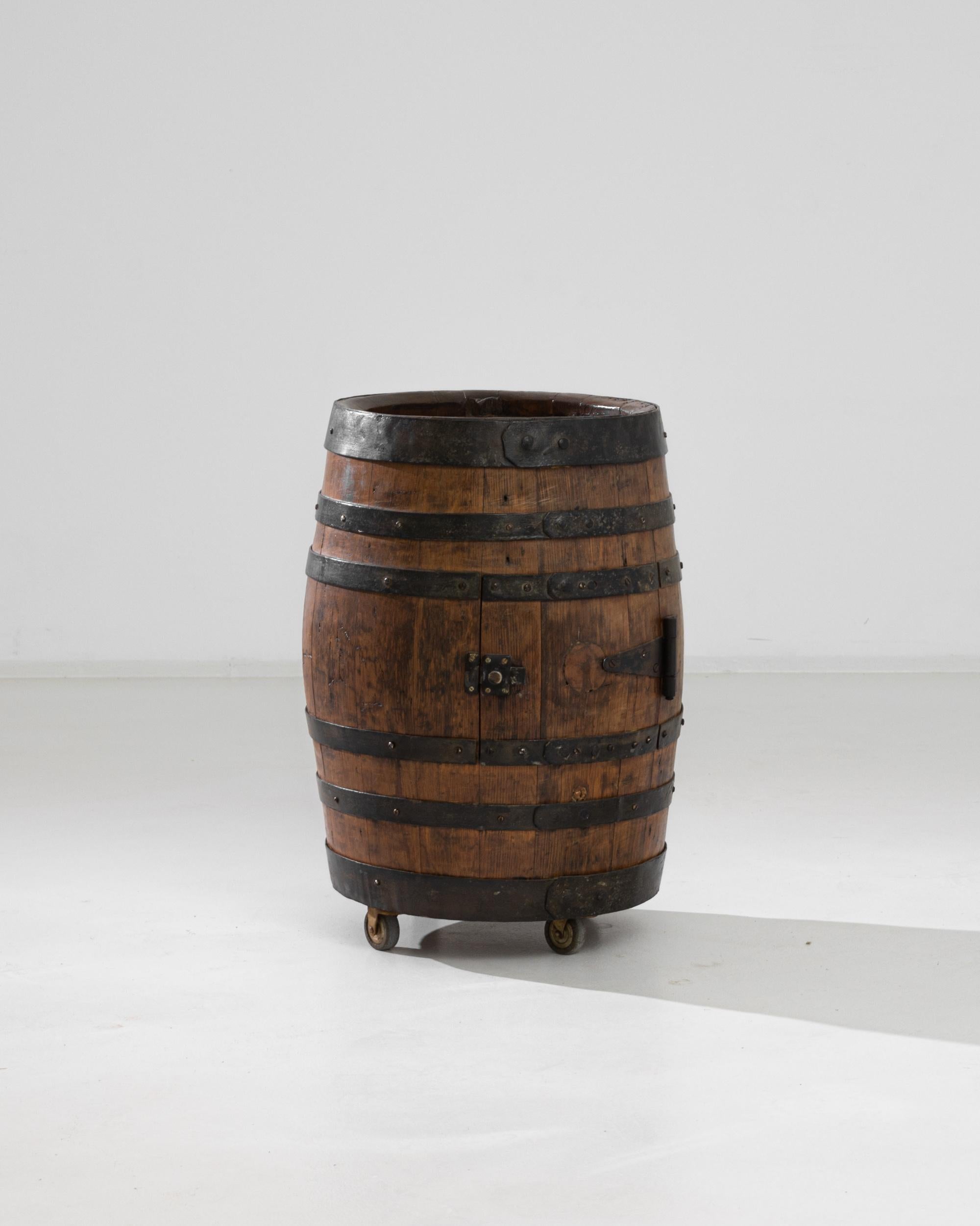 Ce chariot de bar a été fabriqué à partir d'un tonneau de vin original en France au siècle dernier. Le chêne européen à grain serré mais flexible, traditionnellement utilisé pour le façonnage des barils, est entouré d'arceaux métalliques solides