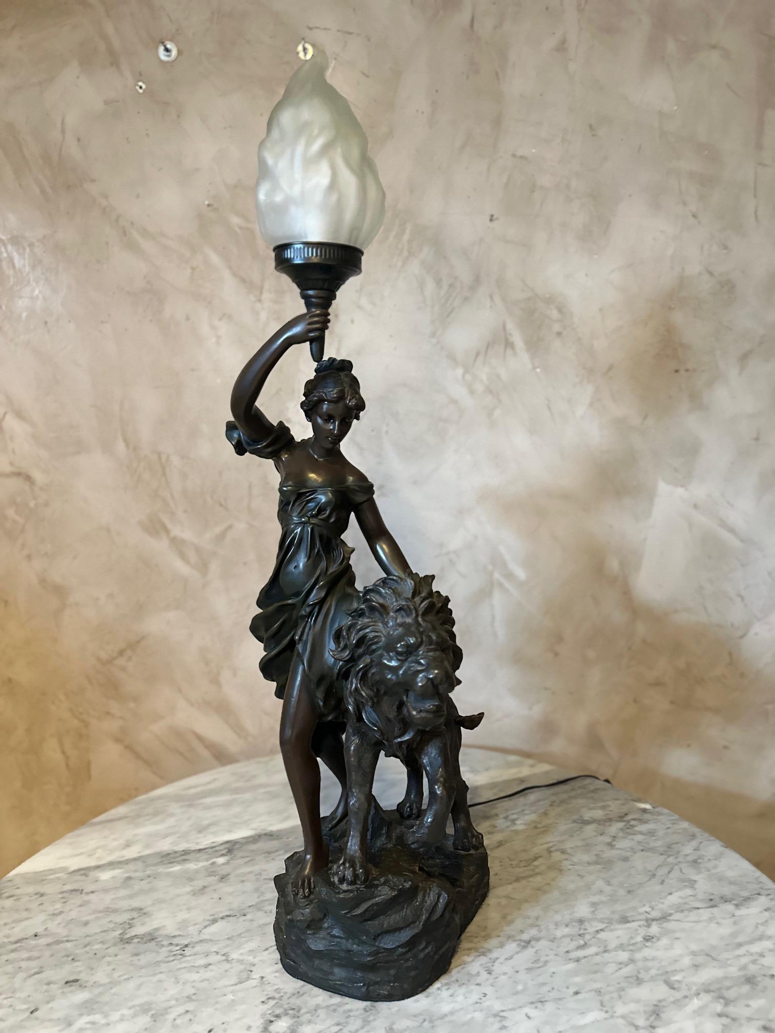 Very beautiful statue made in spelter representing a woman carrying a torch (which lights up) accompanied by a lion. The torch is made with opaline glass. Large size. Nice quality. 
The lion's tail has been broken but overall good condition.