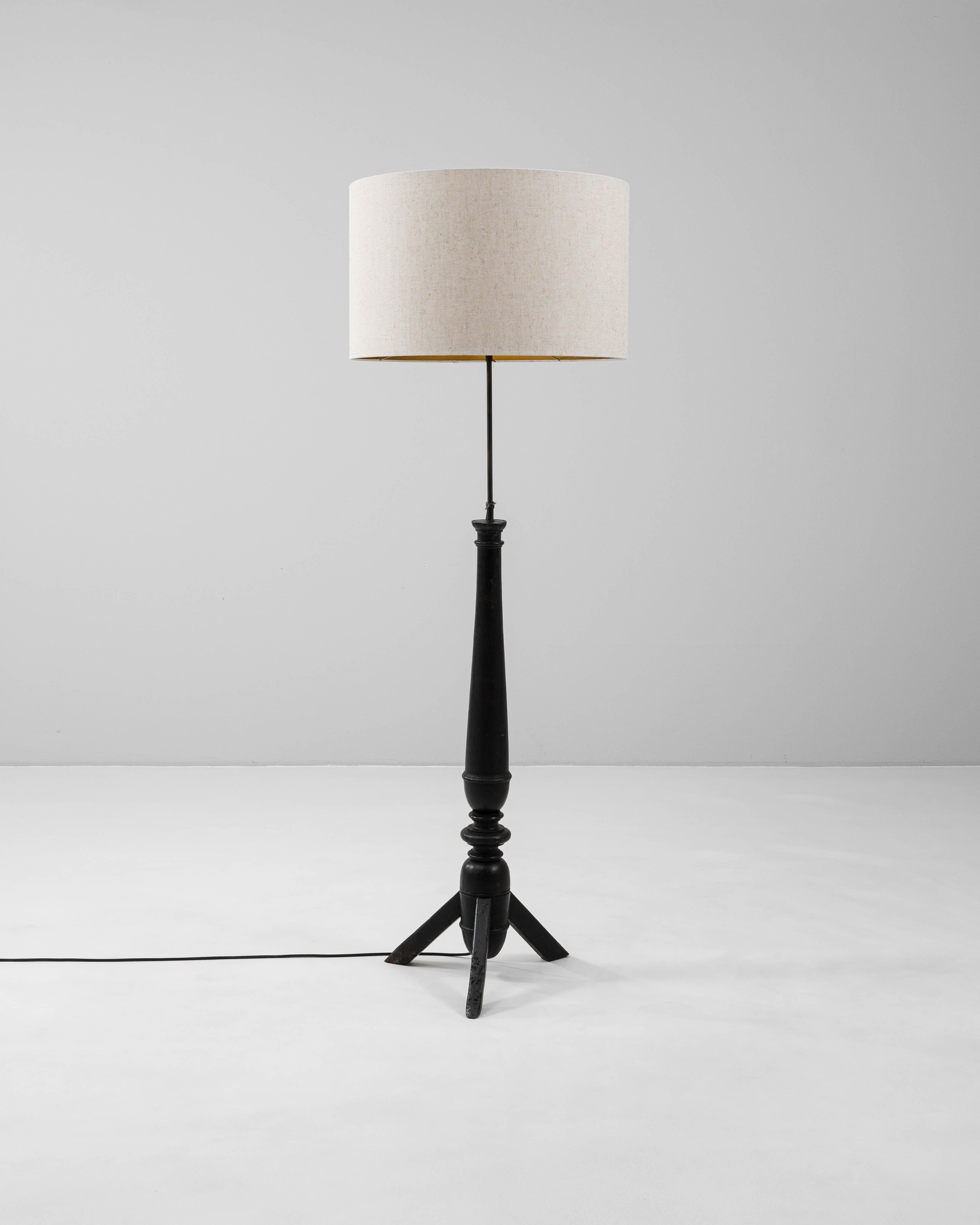 Esta lámpara de pie francesa del siglo XX presenta una base de madera torneada con una rica pátina negra, que añade un atrevido contraste y una elegancia escultural a cualquier espacio. Su forma combina la artesanía tradicional con la utilidad
