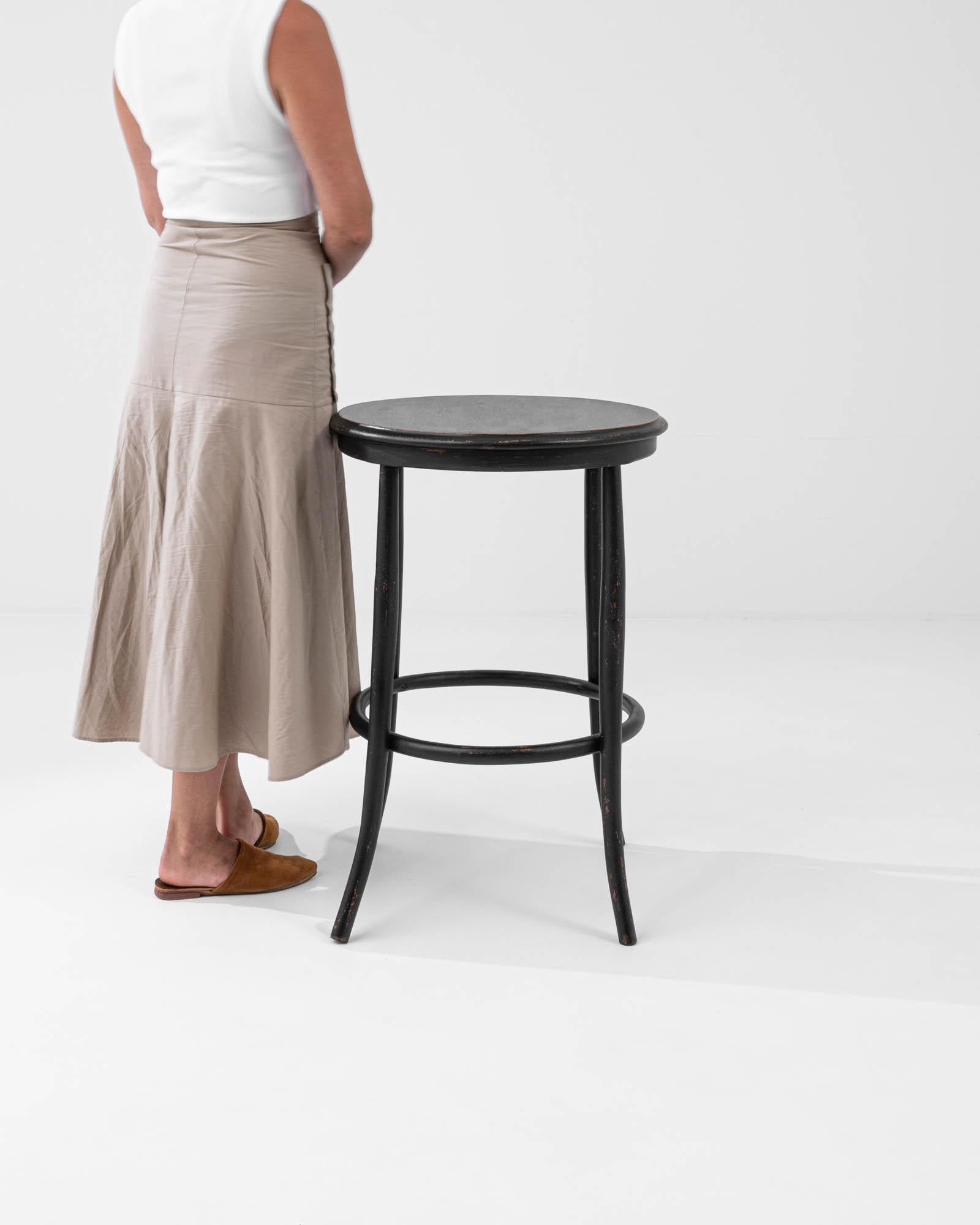 Infuse your space with timeless elegance using this 20th-century French wood black patinated side table. Its design, though simple, exudes sophistication. The circular seat, complemented by a matching rim near the legs, adds a touch of refinement.