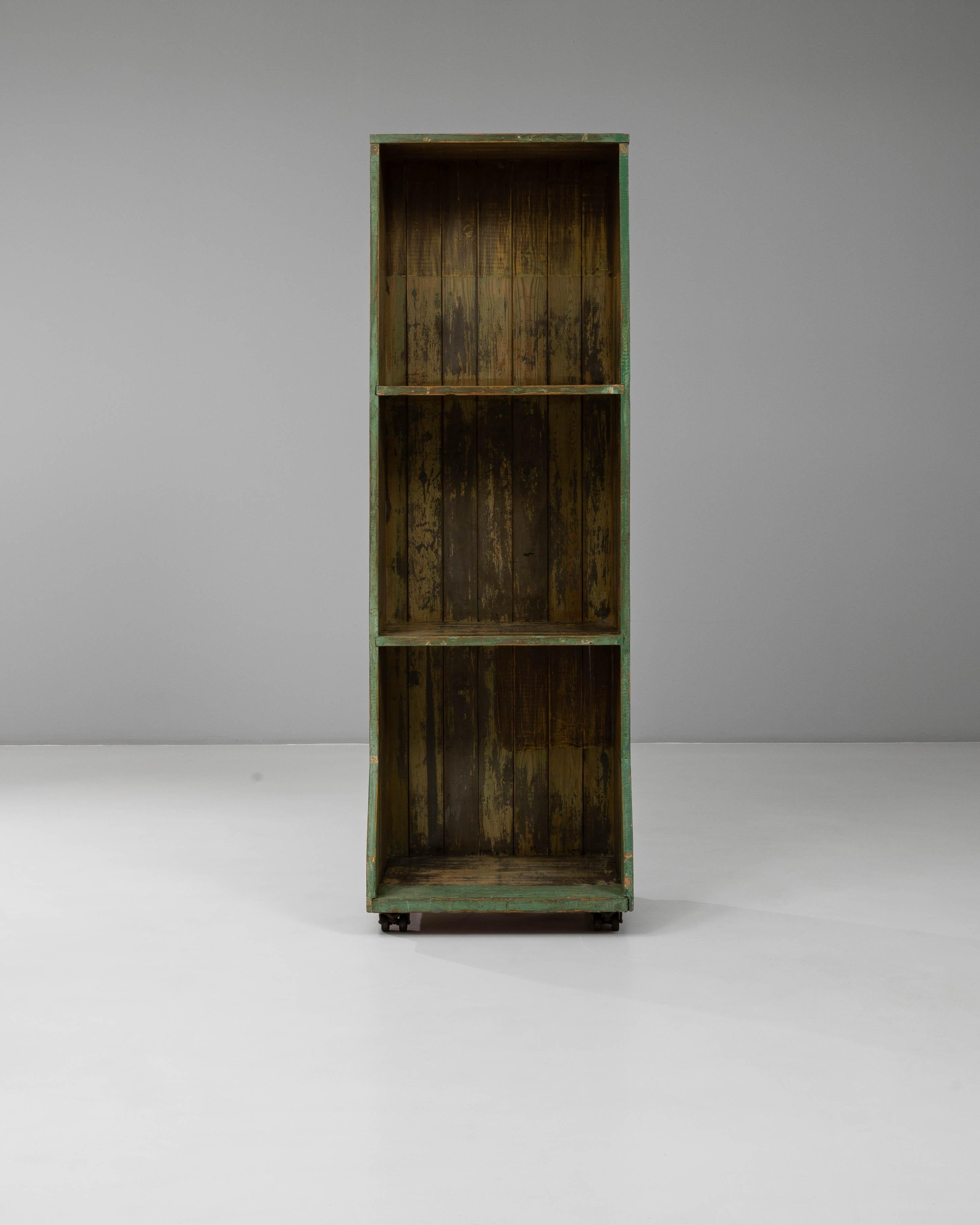 Cette bibliothèque française du 20e siècle présente une patine magnifiquement altérée qui révèle des couches de vert et des tons de bois naturel, ajoutant une touche de charme industriel. Fabriquée en bois massif, cette pièce comporte trois étagères