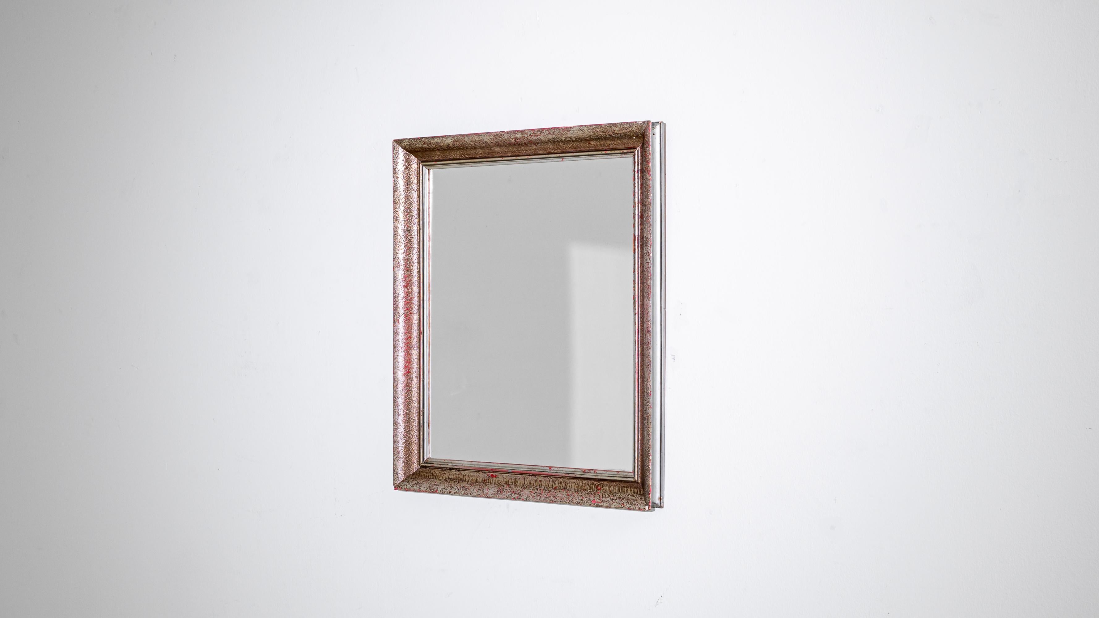 Embrace the understated elegance of this 20th Century French Wood Patinated Mirror. Its simplicity in design speaks volumes, creating a timeless piece that effortlessly complements any space. The mirror features a red undertone gracefully peeking
