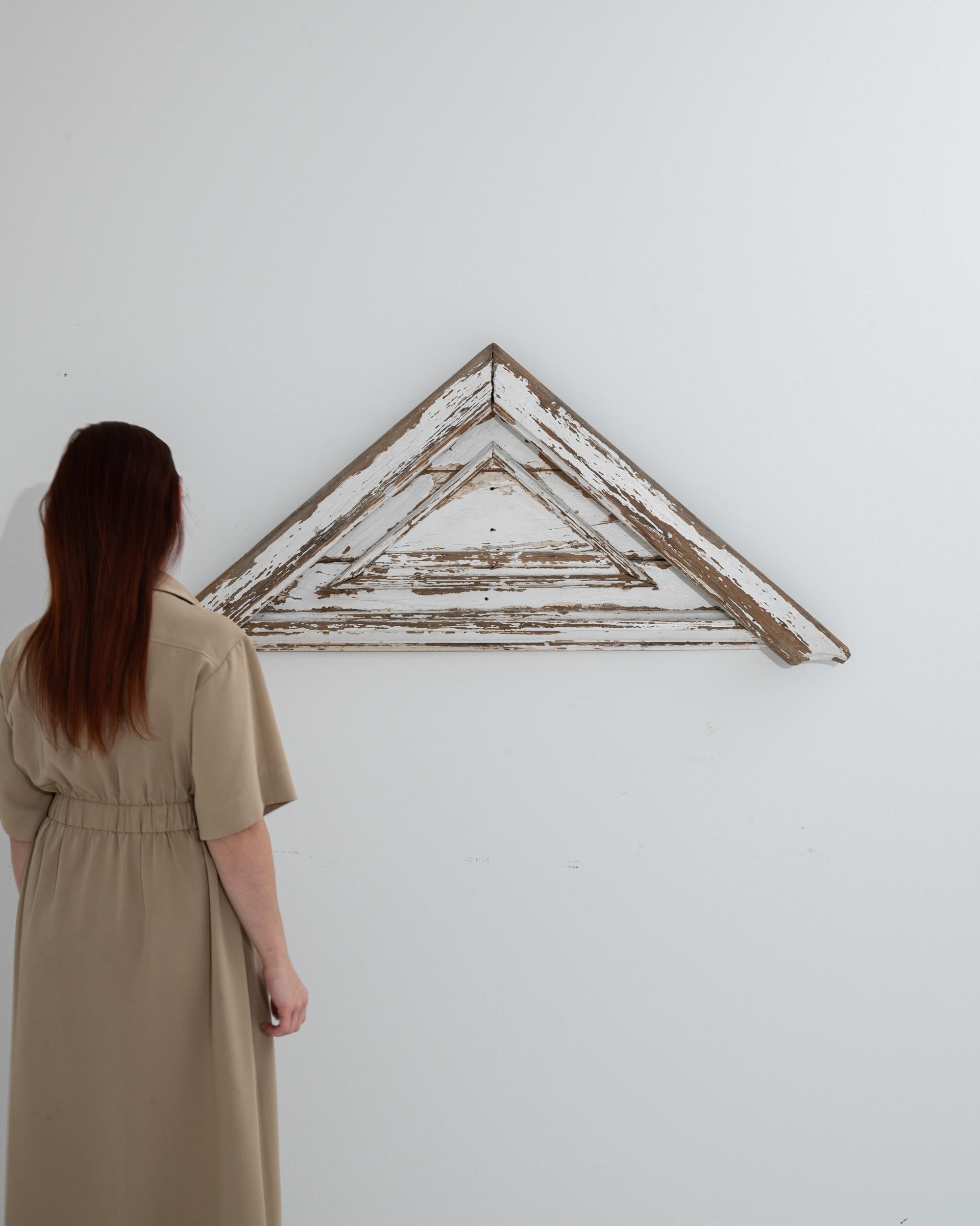 This 20th Century French Wood Patinated Wall Decoration is a rustic gem that brings a touch of antique charm to any contemporary space. Its triangular silhouette, a symbol of stability and creativity, adds a geometric edge to walls that crave