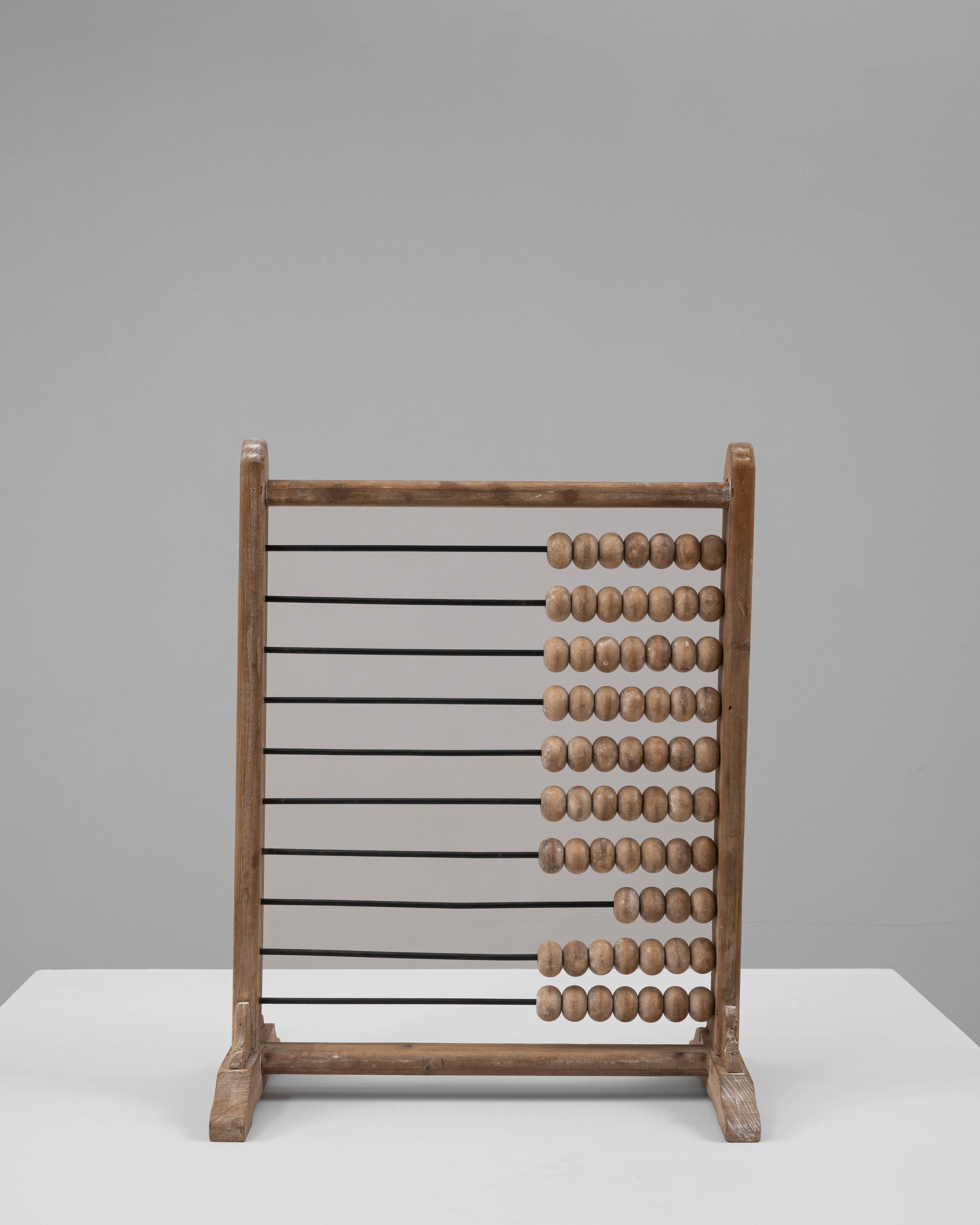This 20th-century French wooden abacus is a charming example of vintage educational tools. Constructed from solid wood, it features smooth, natural-finished wooden beads strung on sturdy metal rods, all supported by a robust wooden frame with