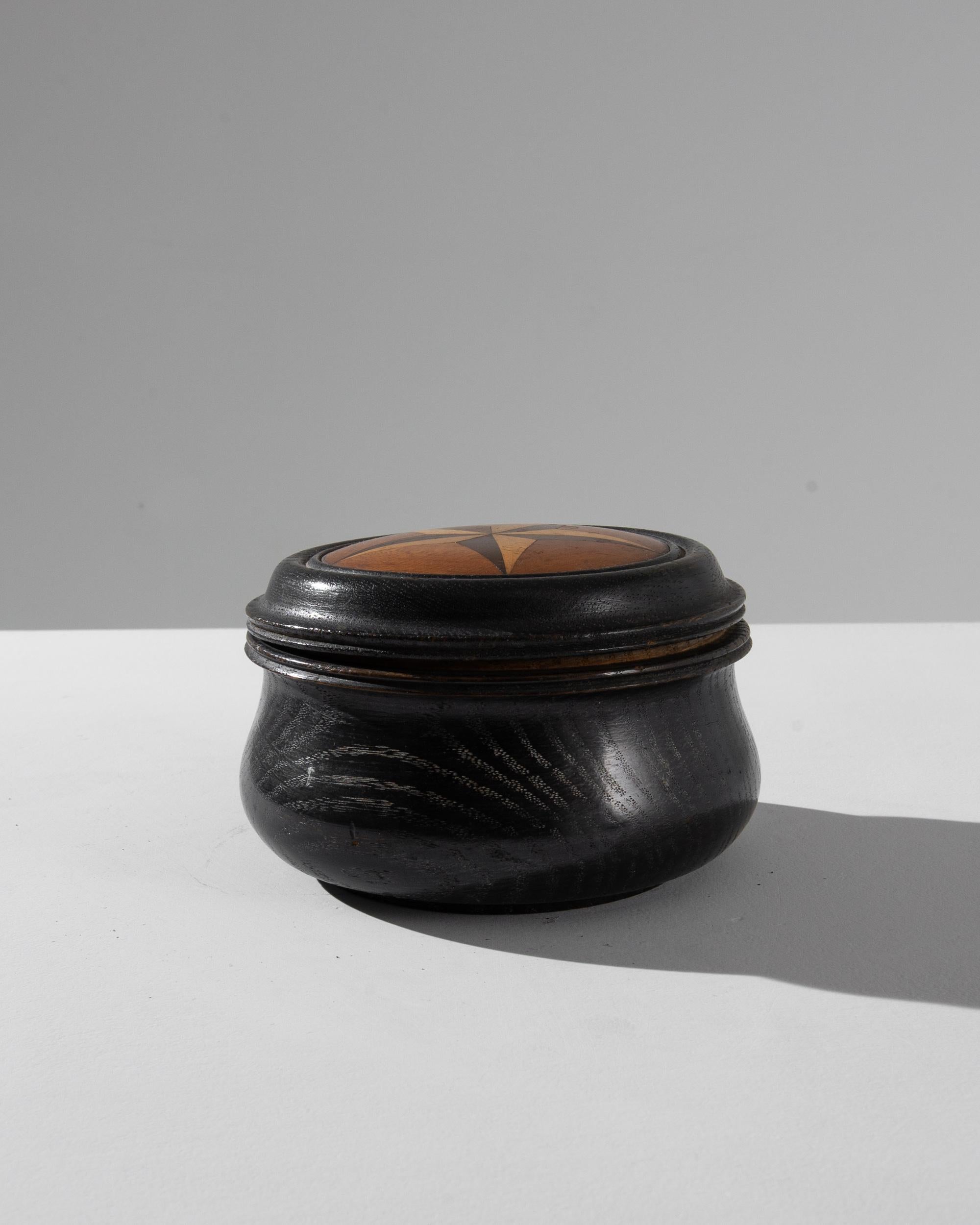 A 20th century polished wooden box produced in France, this antique mysterious object showcases a full shape and a lush black finish. 
Adorned with an inlaid five pointed star made of a fine marquetry work, the small box exhibits a lush variety of