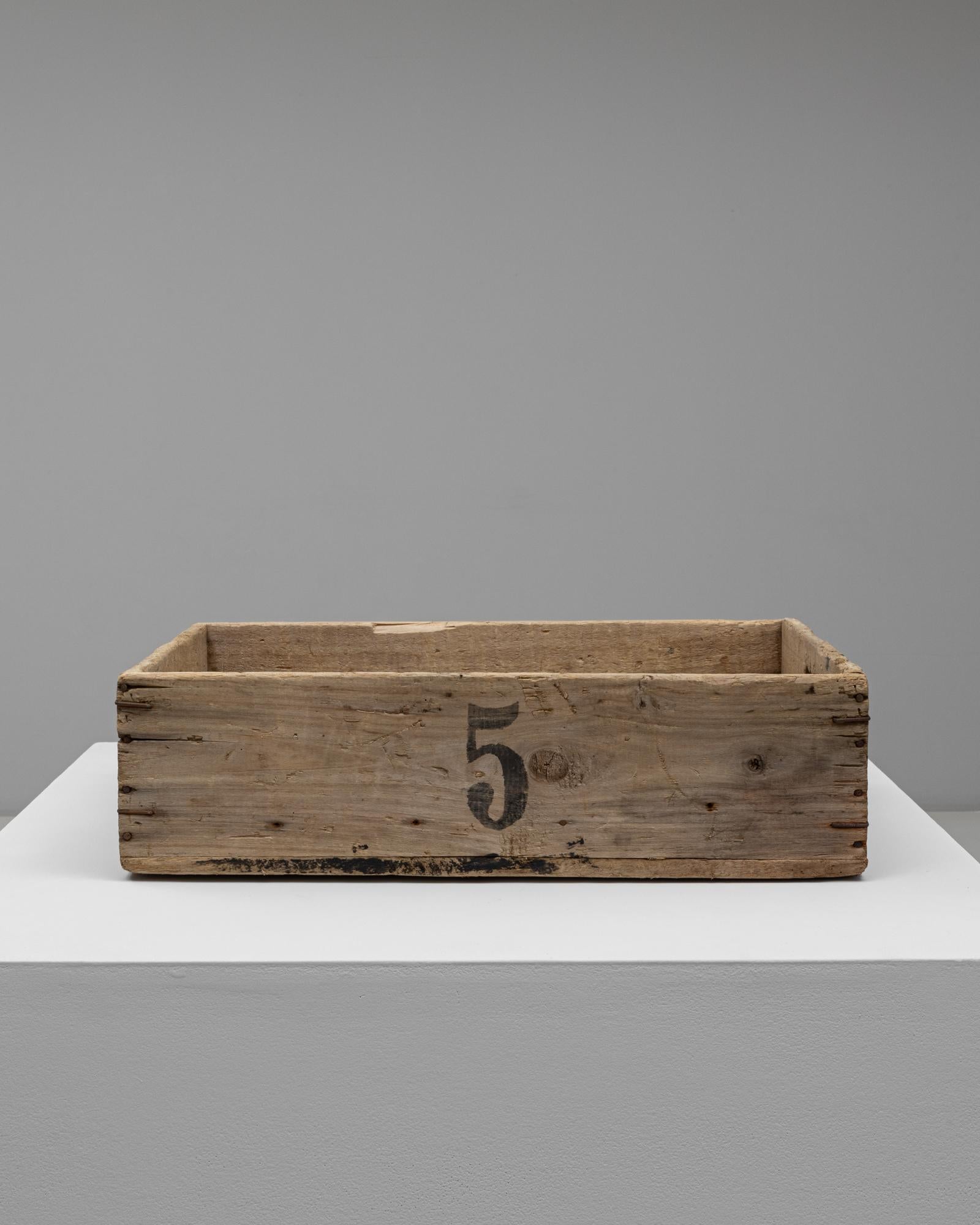 This 20th Century French wooden box highlights the simplicity and character of utilitarian French design. Constructed from solid, weathered wood, it features hand-cut joinery, iron nail detailing, and a naturally aged patina that enhances its rustic