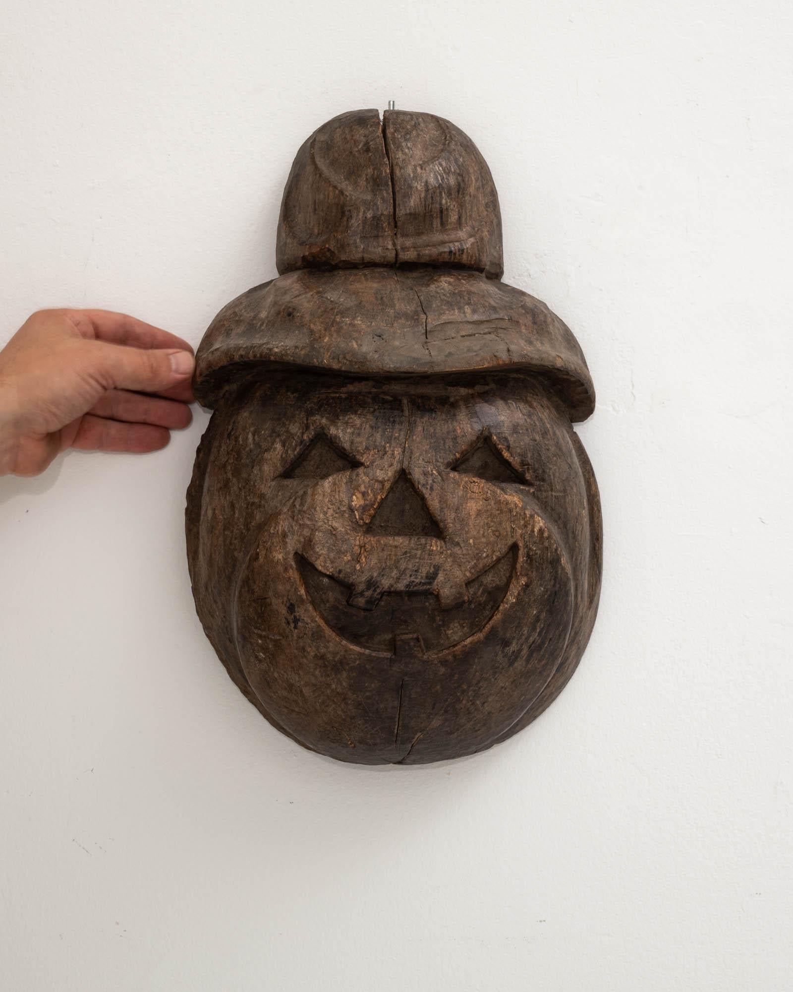 Enchant your space with the whimsical charm of this 20th-century French Wooden Carved Pumpkin Wall Decoration. Crafted with precision, the pumpkin's friendly face comes to life, featuring classic triangle eyes, a jovial smile, and a nose that adds