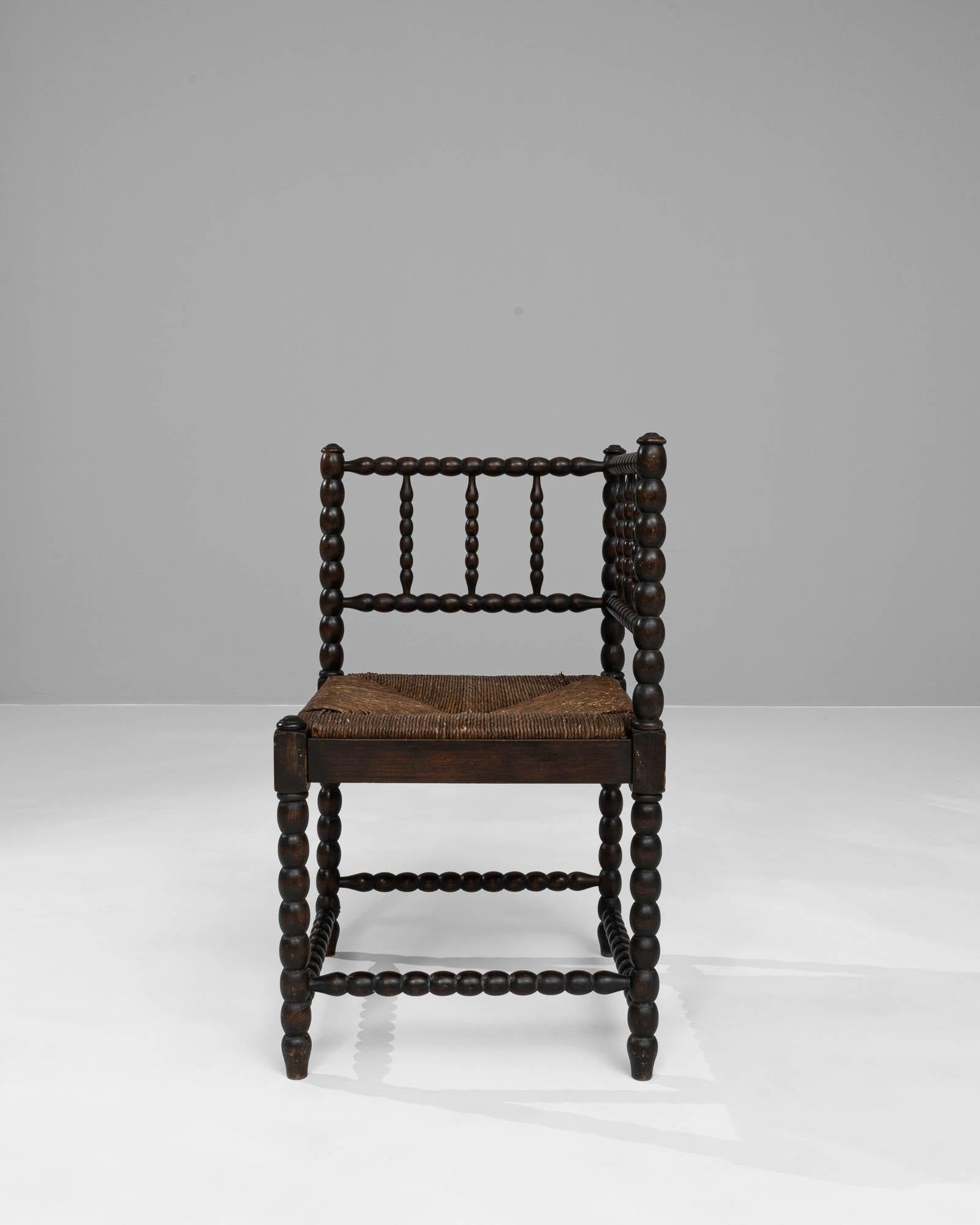 Imbued with the essence of French craftsmanship, this 20th Century Wooden Chair presents itself as a classic addition to any discerning collector's ensemble. Each spindle, a series of perfectly turned beads, creates a harmonious flow throughout the