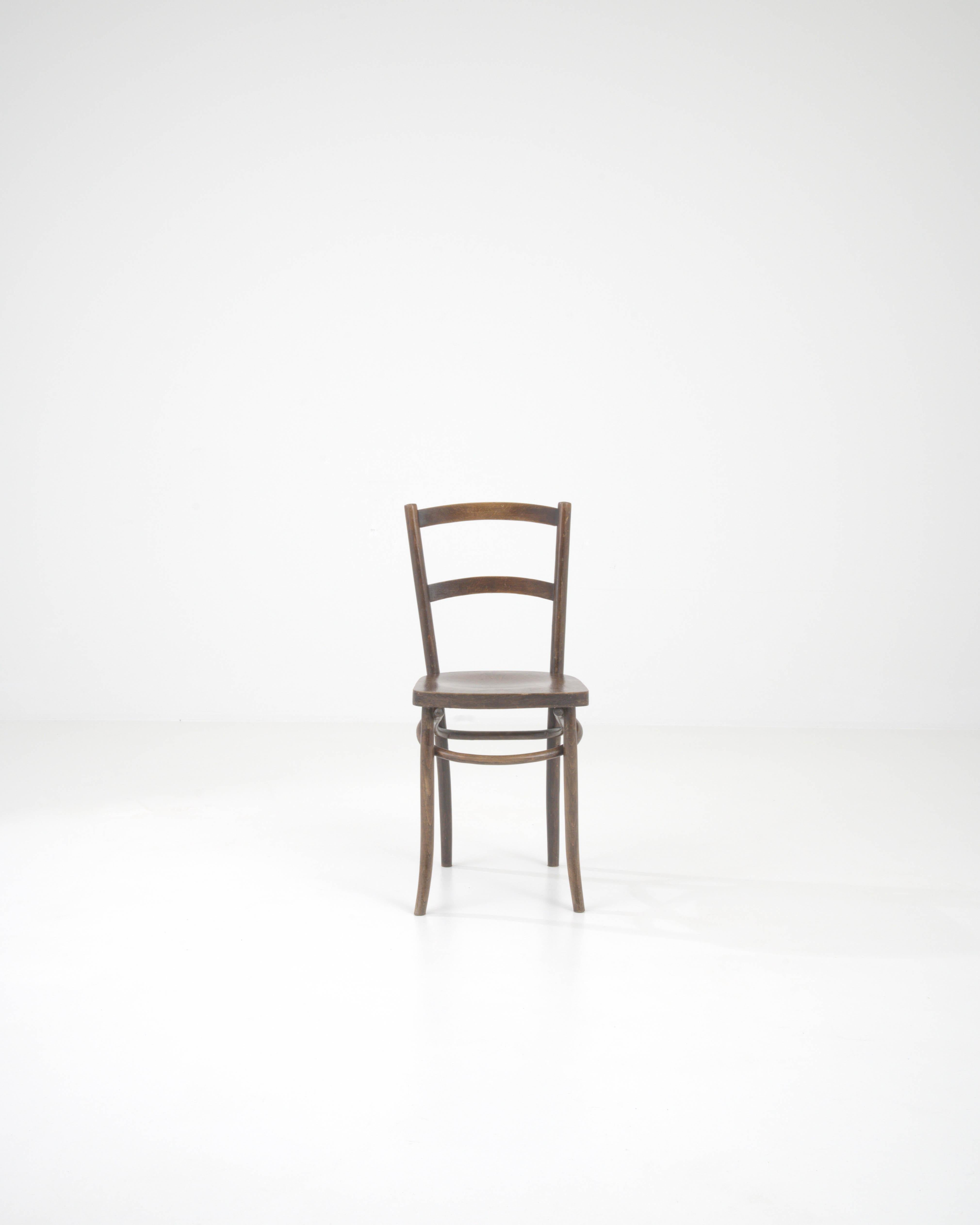 La chaise en bois française du 20e siècle est l'incarnation de l'élégance intemporelle et de l'artisanat d'antan. Conçue avec un clin d'œil à l'esthétique classique, cette chaise présente une patine chaude et riche qui murmure des histoires