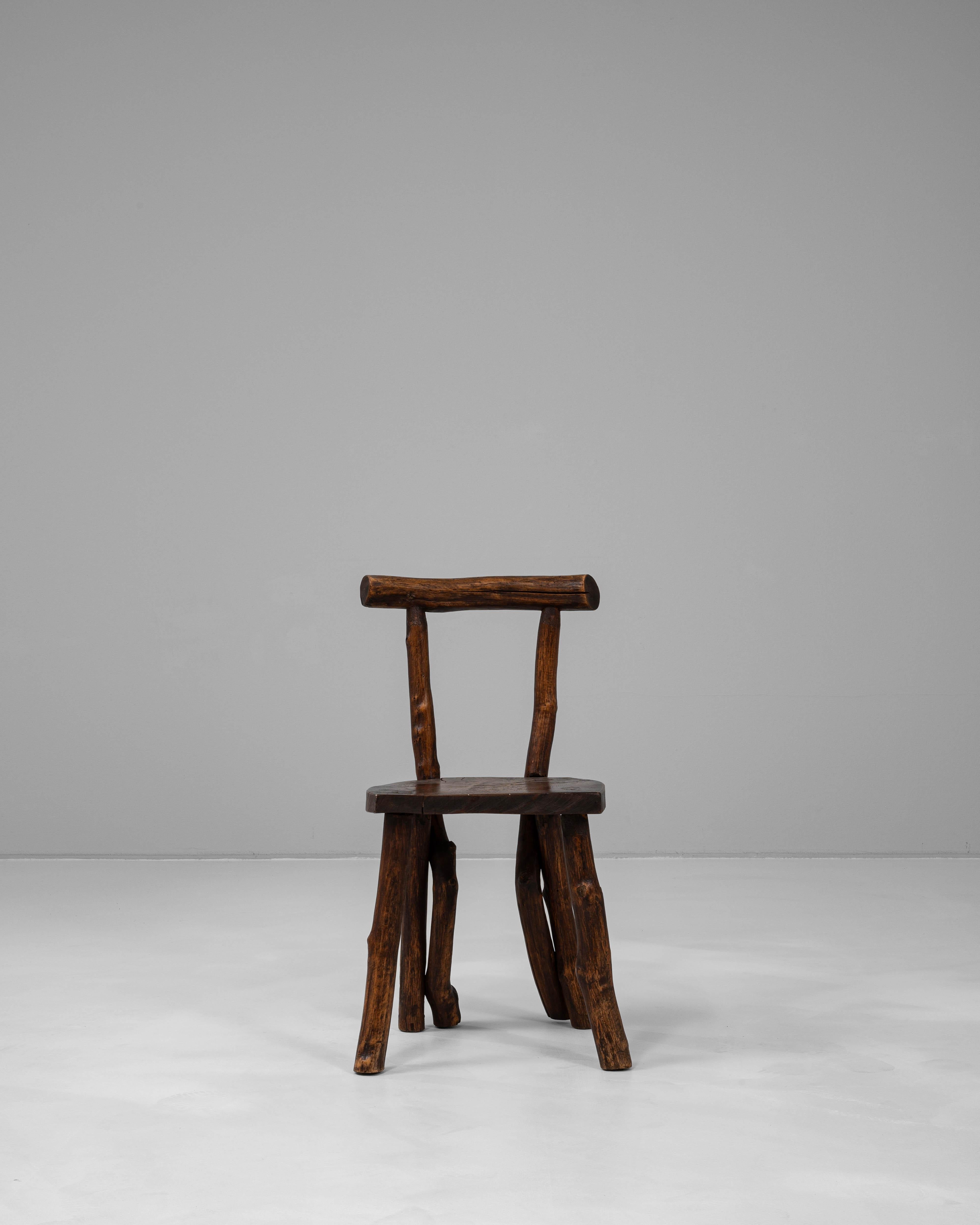 This 20th Century French wooden chair embodies a raw, organic aesthetic with its hand-carved construction and use of naturally shaped timber. Each component retains the irregular curves and textures of the original wood, celebrating the