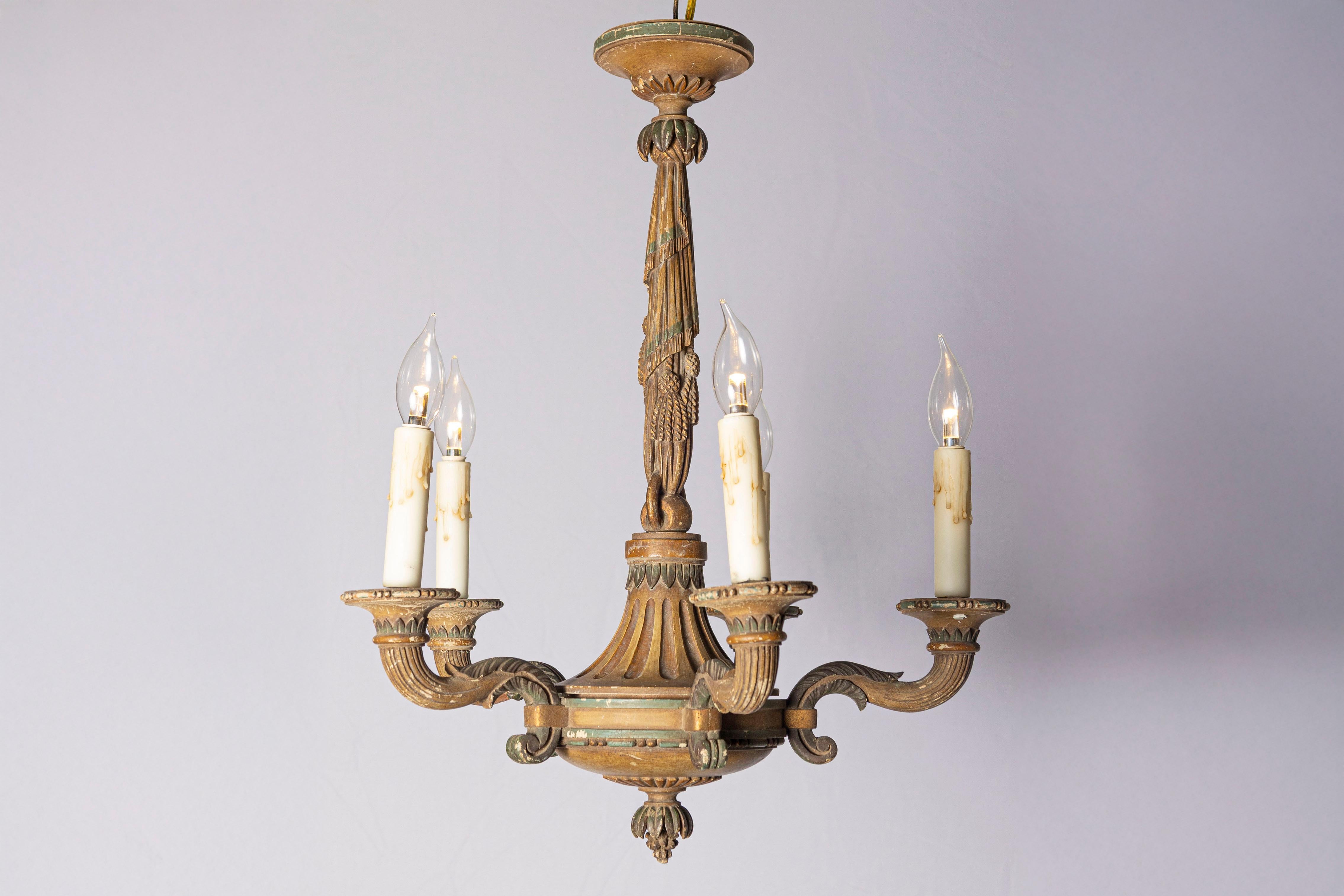 This charming 20th-century French wooden chandelier embodies the elegance of classic French craftsmanship. Crafted from finely carved wood, it features intricate details that showcase an aged patina, adding character and depth. The chandelier holds