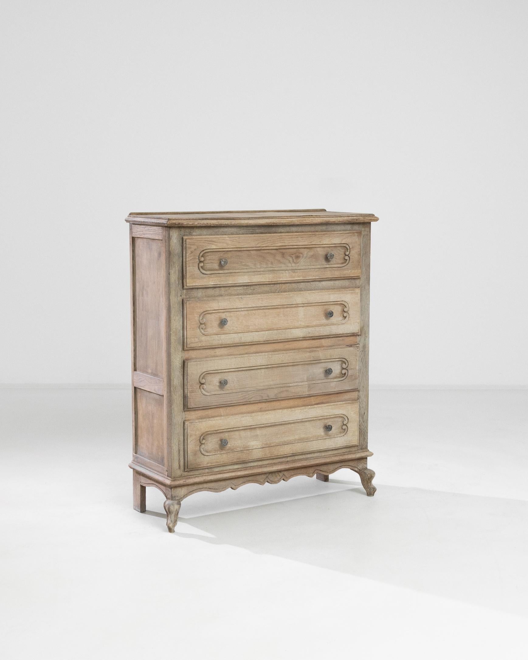 A 20th century chest of drawers from France, this piece features four front drawers, a scalloped apron with shell detail and french cabriole feet. The drawers are carved with elegant volutes and embellished with fleuret brass knobs with gilded