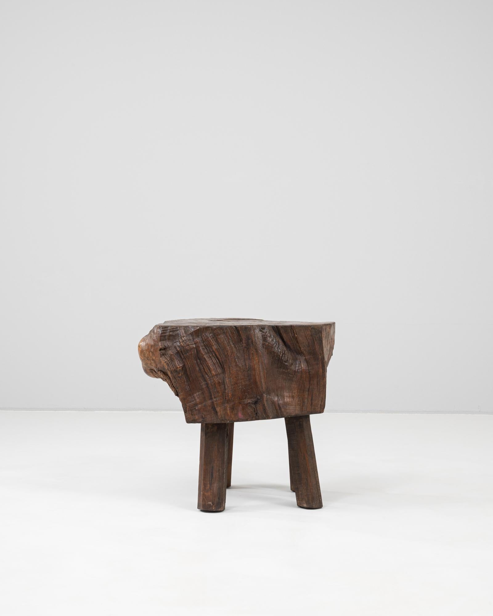 This 20th Century French wooden coffee table is a sculptural statement piece hewn from a single, massive block of hardwood. Retaining its raw, organic form, the table top showcases a rich patina, deep grain, and visible tool marks that speak to its