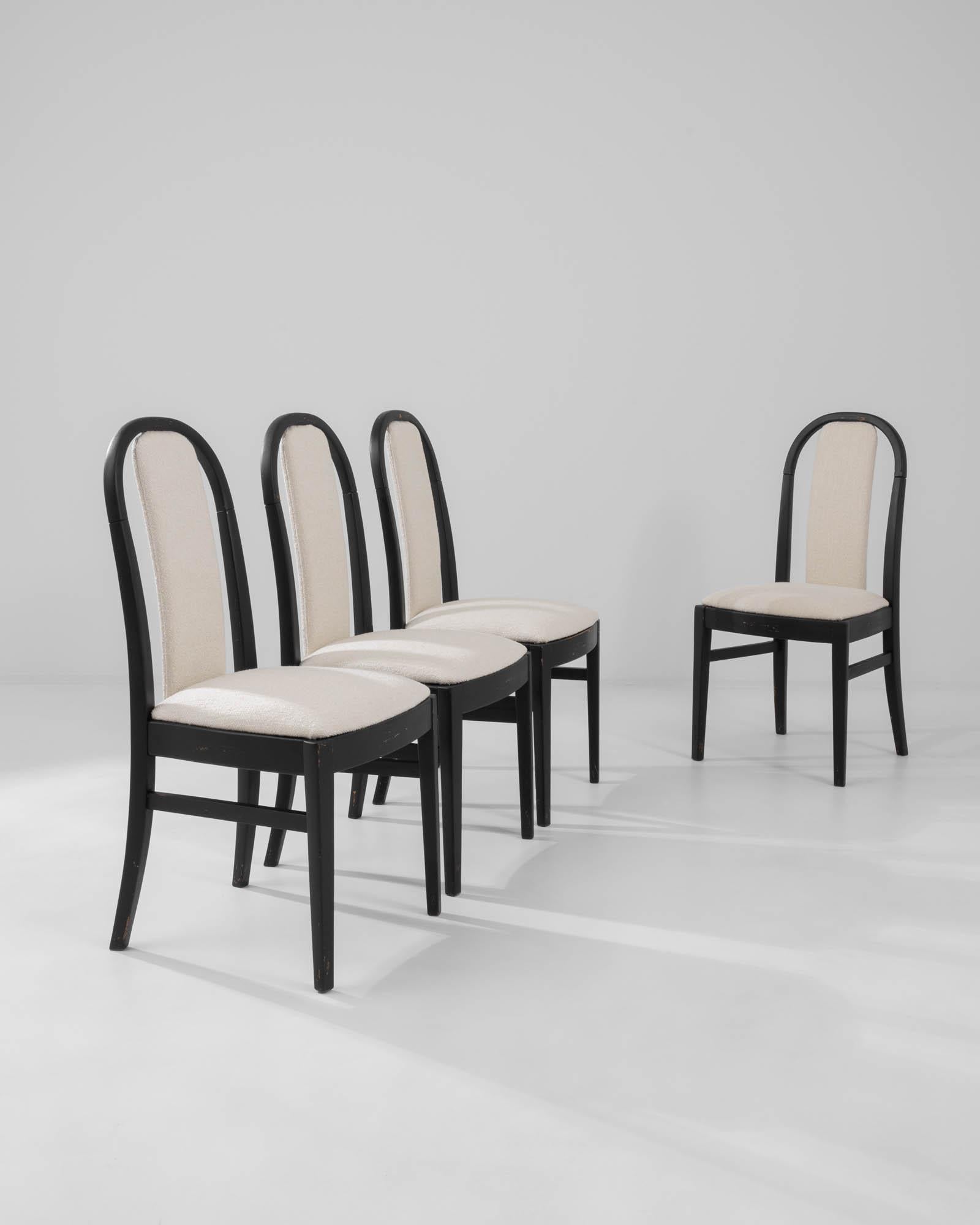 Impeccably stylish, this set of four wooden dining chairs make a sophisticated addition to intimate soirees and elegant gatherings. Built in France in the 20th century, the design has a Modernist simplicity. The clean curve of the backrest is