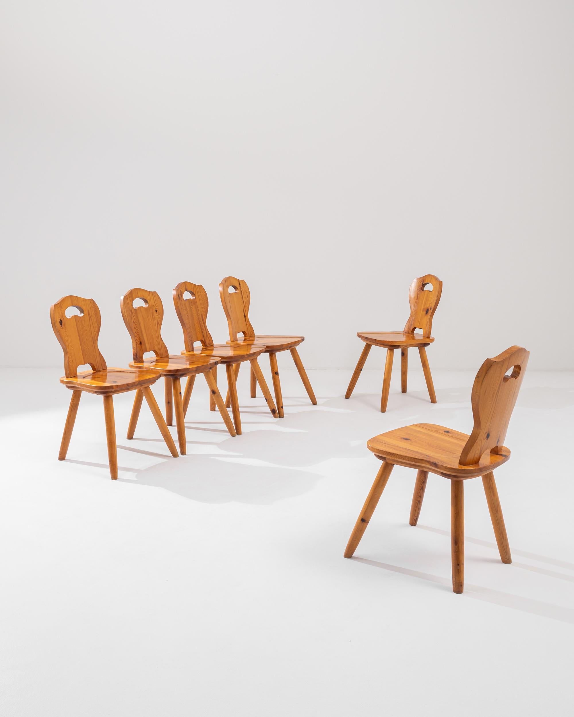 A set of six 20th century wooden dining chairs produced in France, these lustrous chairs impart a sophisticated simplicity. Standing on splayed tapered legs, the modern Silhouette lays special focus on the richness of the wood, highlighting its