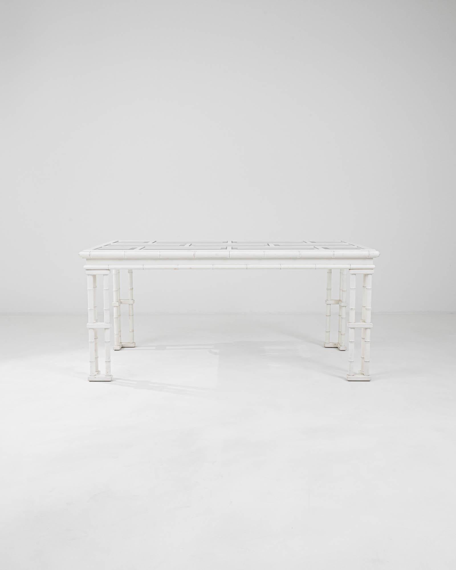 Immerse yourself in the allure of this 20th Century French Wooden Dining Table, a paragon of chic sophistication. Its white-painted bamboo-style frame provides a fresh and airy feel, perfect for brightening up any dining space. The table's glass top